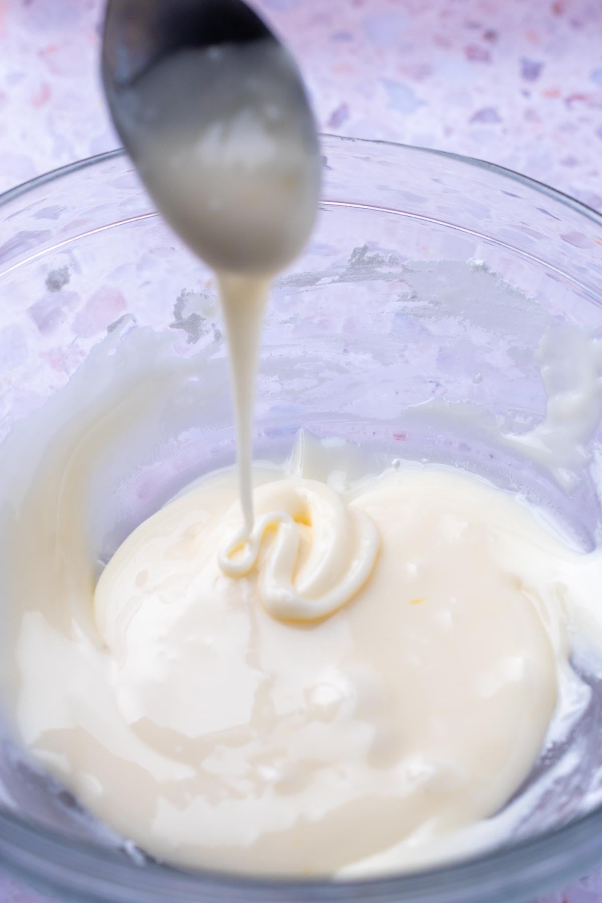 Spoon with drizzle of orange icing into bowl.
