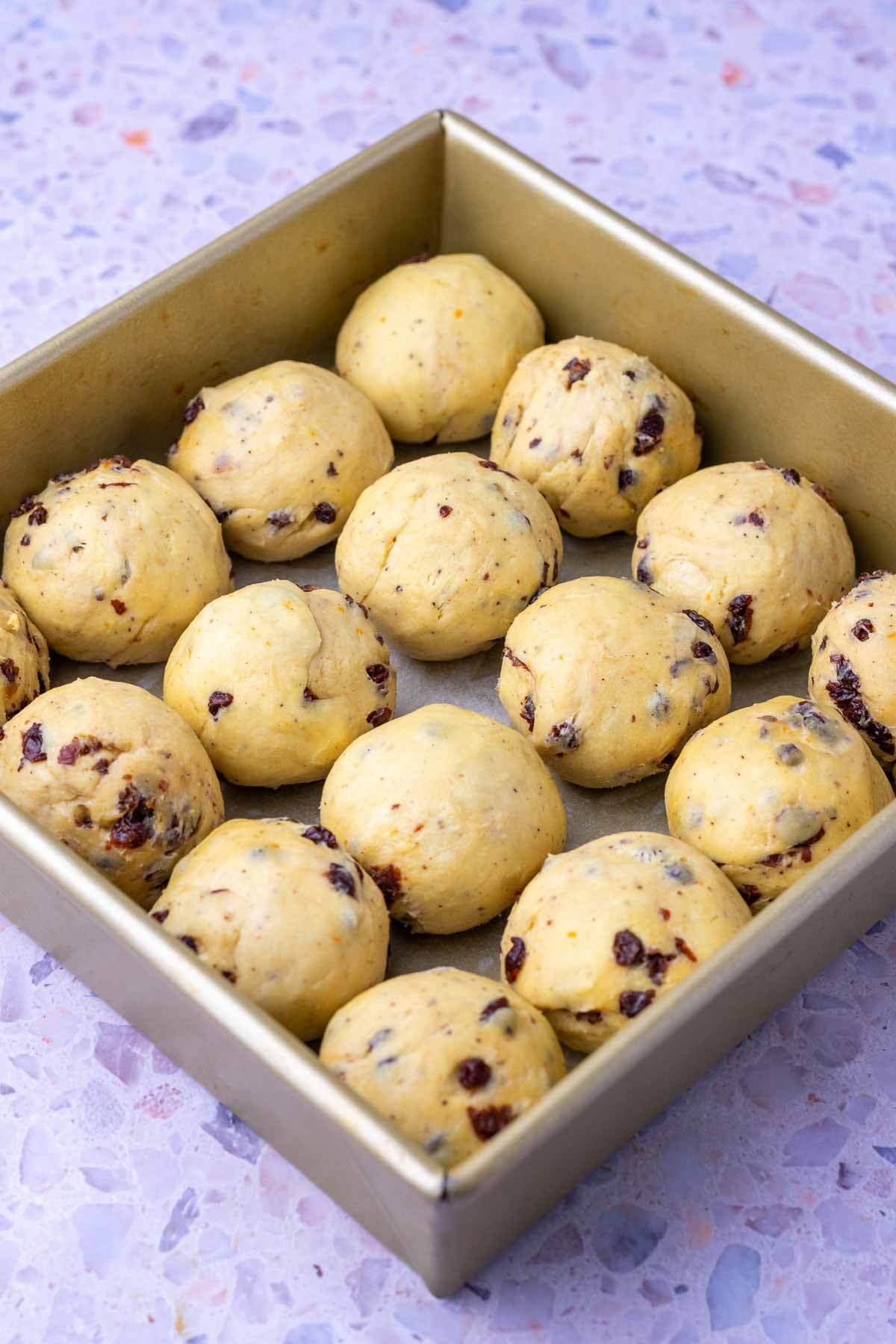 Shaped sourdough hot cross buns in a 9-inch square baking dish