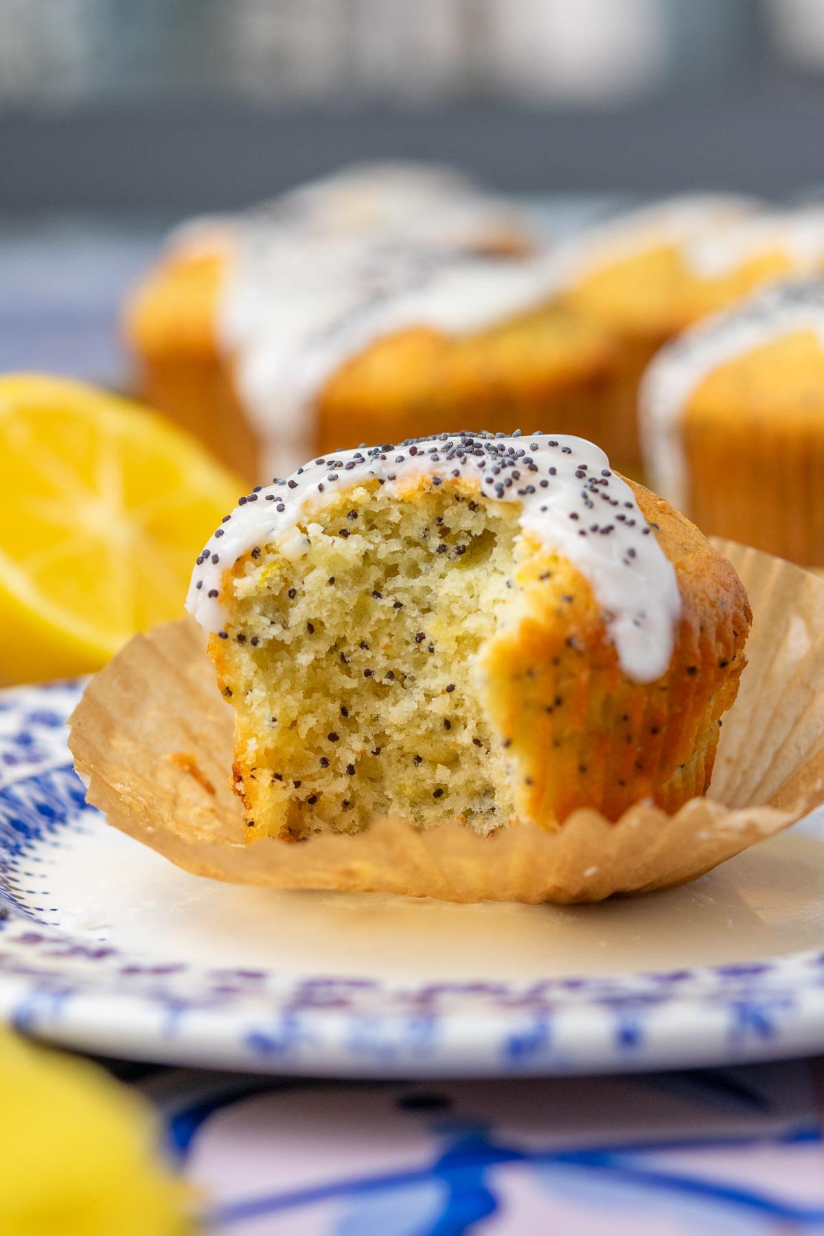 Bite taken out of a sourdough lemon poppy seed muffin on a plate.