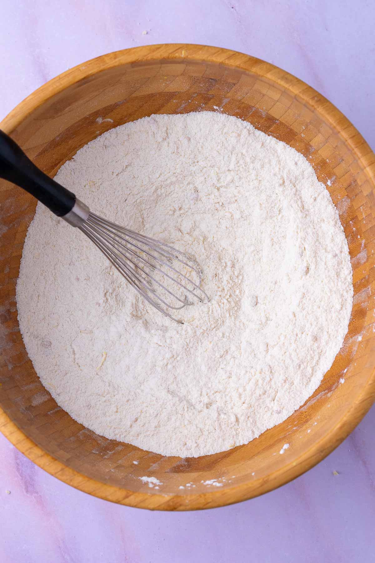 Bowl of dry ingredients for Sourdough strawberry muffins with a whisk.
