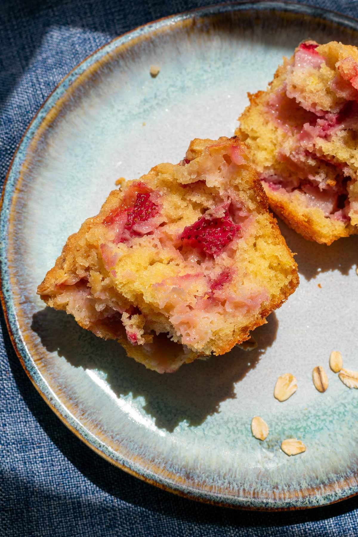 Interior of a fluffy Sourdough strawberry muffin on a plate with oat crumb topping.