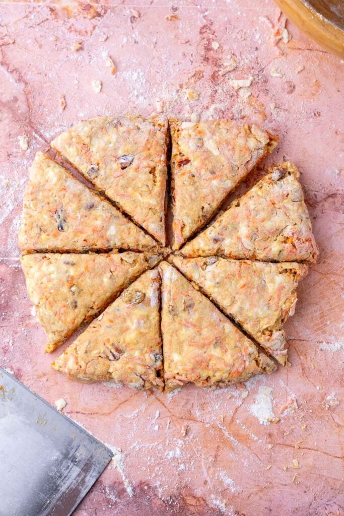 Sliced sourdough carrot cake scones into eight triangles with a bench scraper.