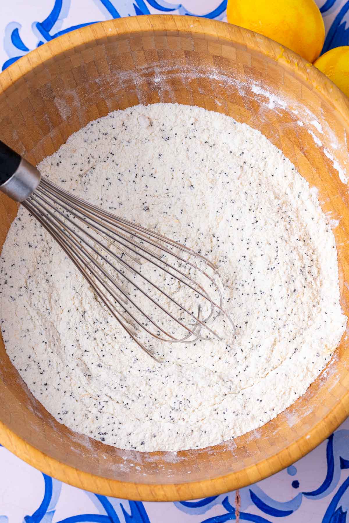 Dry ingredients mixed in bowl with whisk for sourdough lemon poppy seed muffins.
