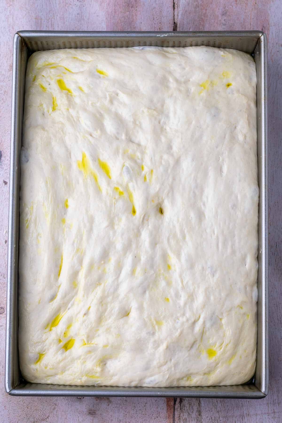 Sourdough focaccia dough in a baking pan doubled in size at the end of final proof.