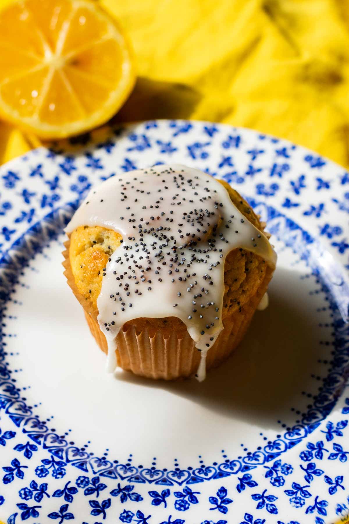 Sourdough lemon poppy seed muffin on a plate topped with lemon glaze and poppy seeds.