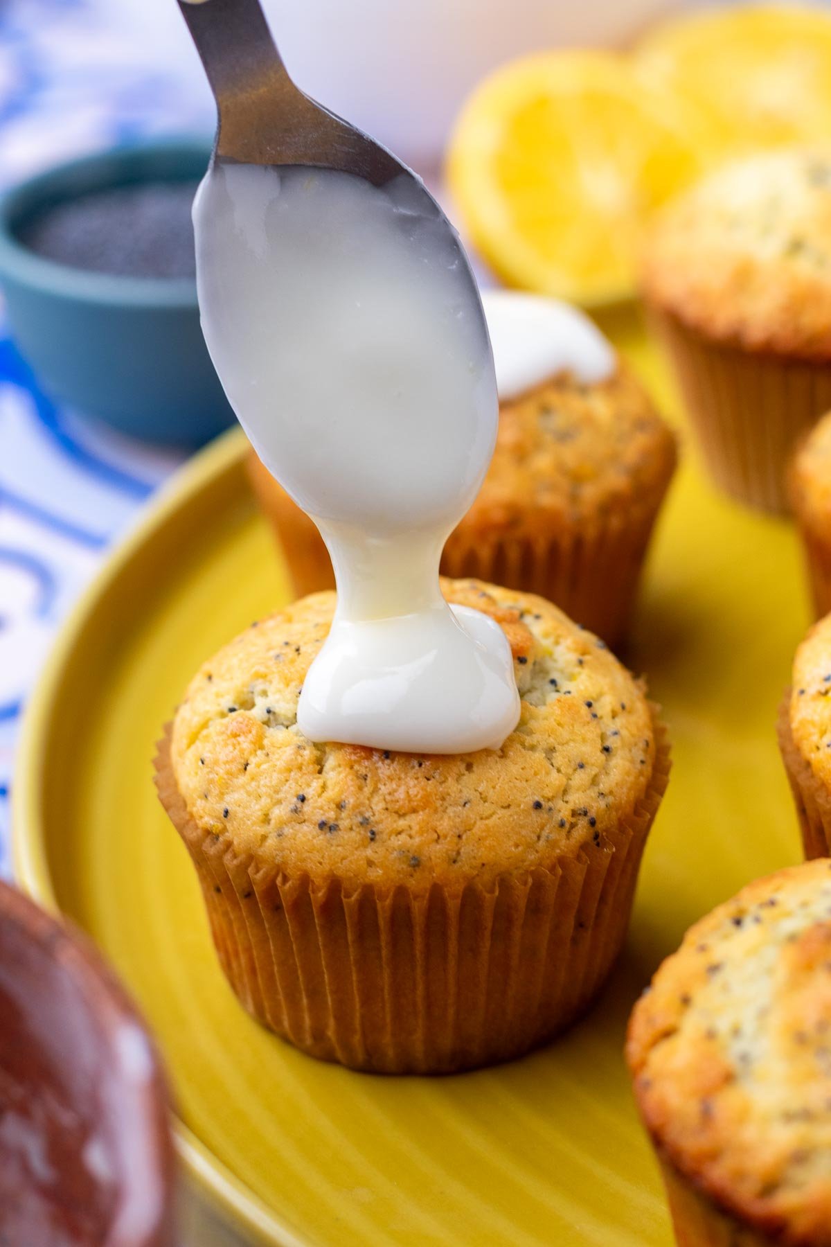 Spooning lemon glaze on top of a sourdough lemon poppy seed muffin.