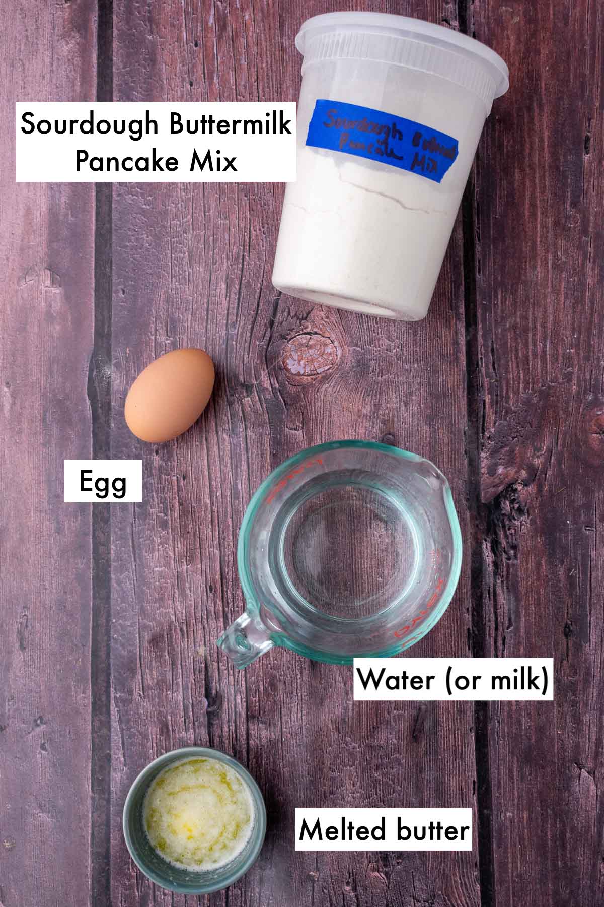 Labeled ingredients needed to make sourdough buttermilk pancakes including water, egg, melted butter, and sourdough dry buttermilk pancake mix.