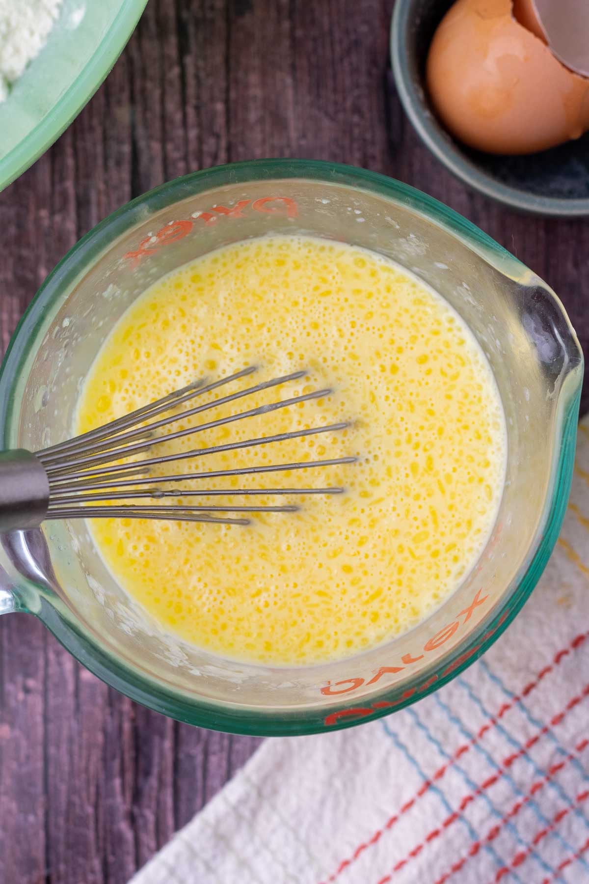 Whisking wet ingredients for sourdough buttermilk pancakes in a liquid measuring cup.