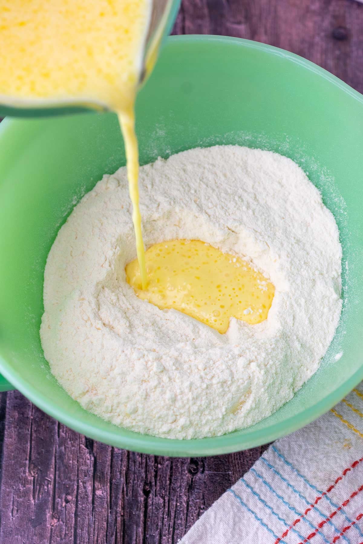Pouring the wet ingredients into a bowl of dry sourdough buttermilk pancake mix.