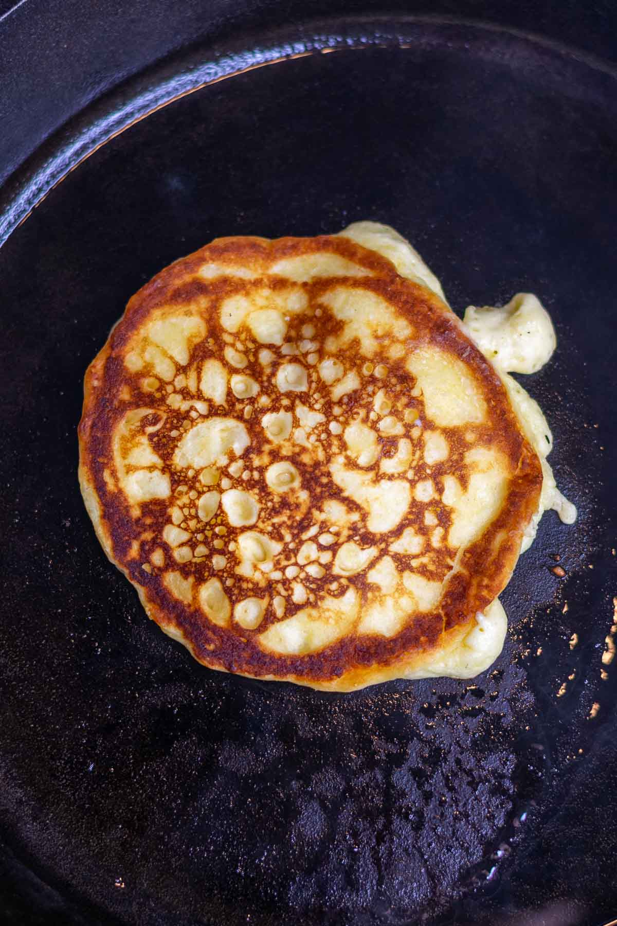 Cooked fluffy sourdough buttermilk pancake in a cast-iron skillet with crispy edges.