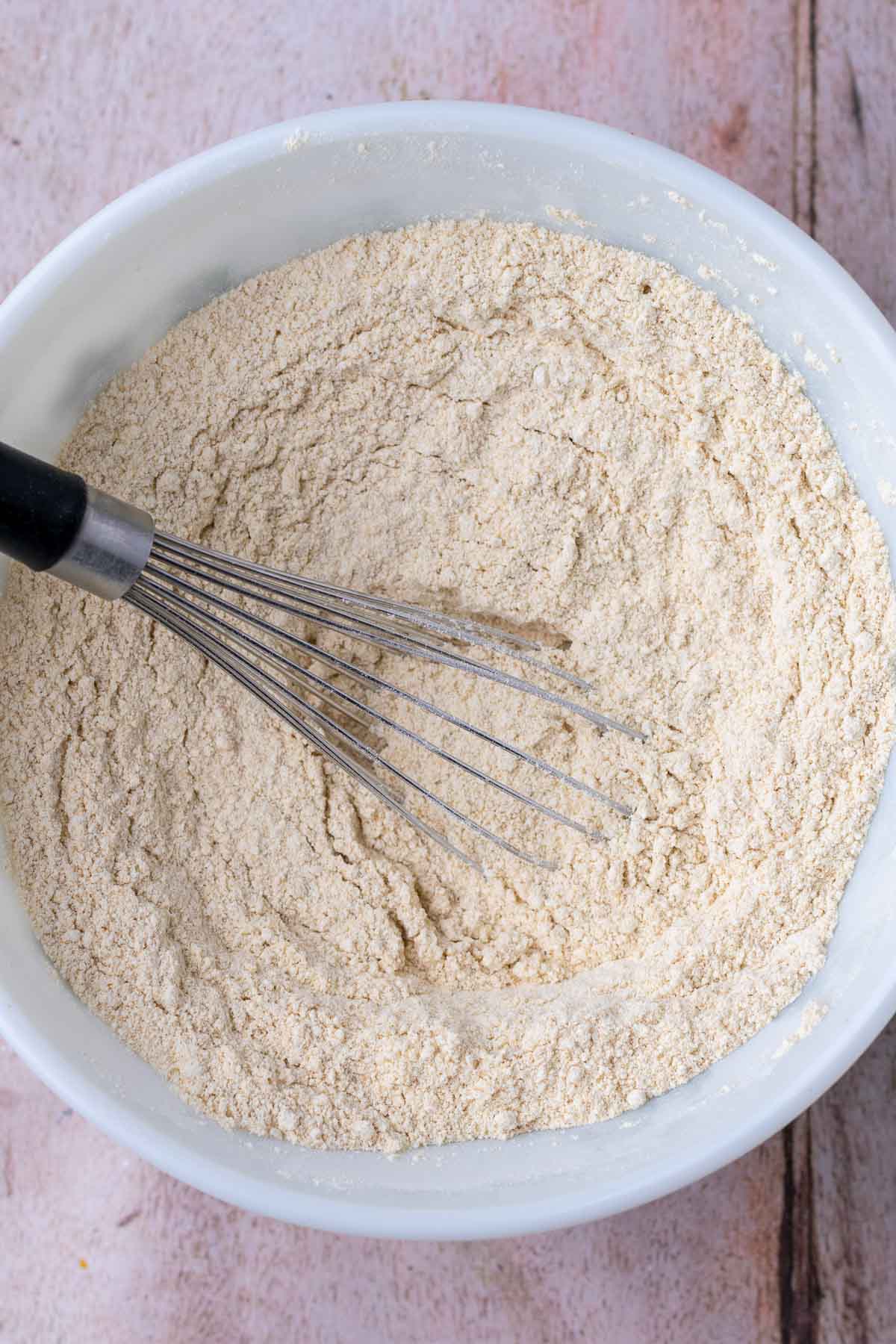 Bowl of mixed dry ingredients for sourdough einkorn waffles with a whisk.