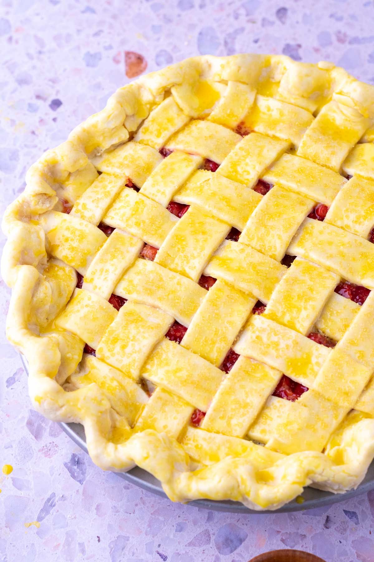 Egg wash and raw sugar on a lattice topped sour cherry pie before baking.