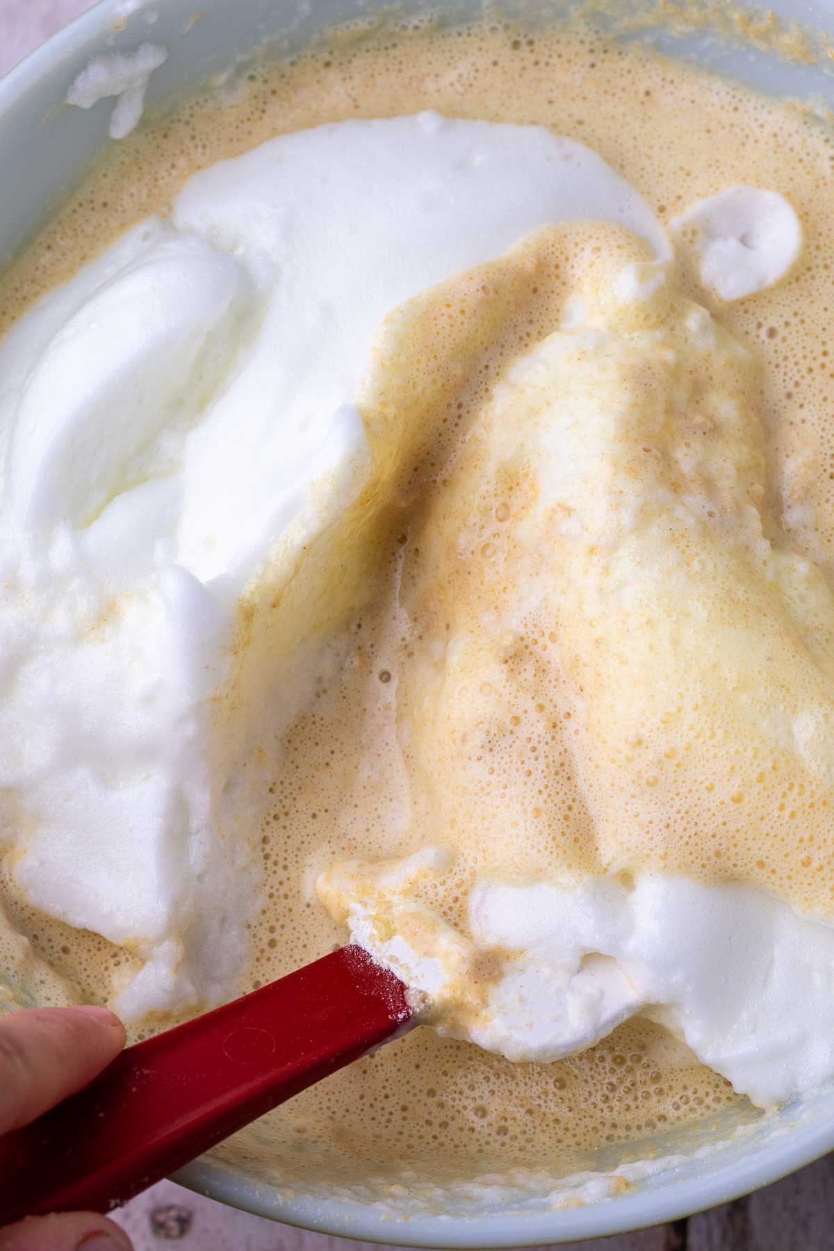 Spatula folding whipped egg whites into sourdough einkorn waffle batter.
