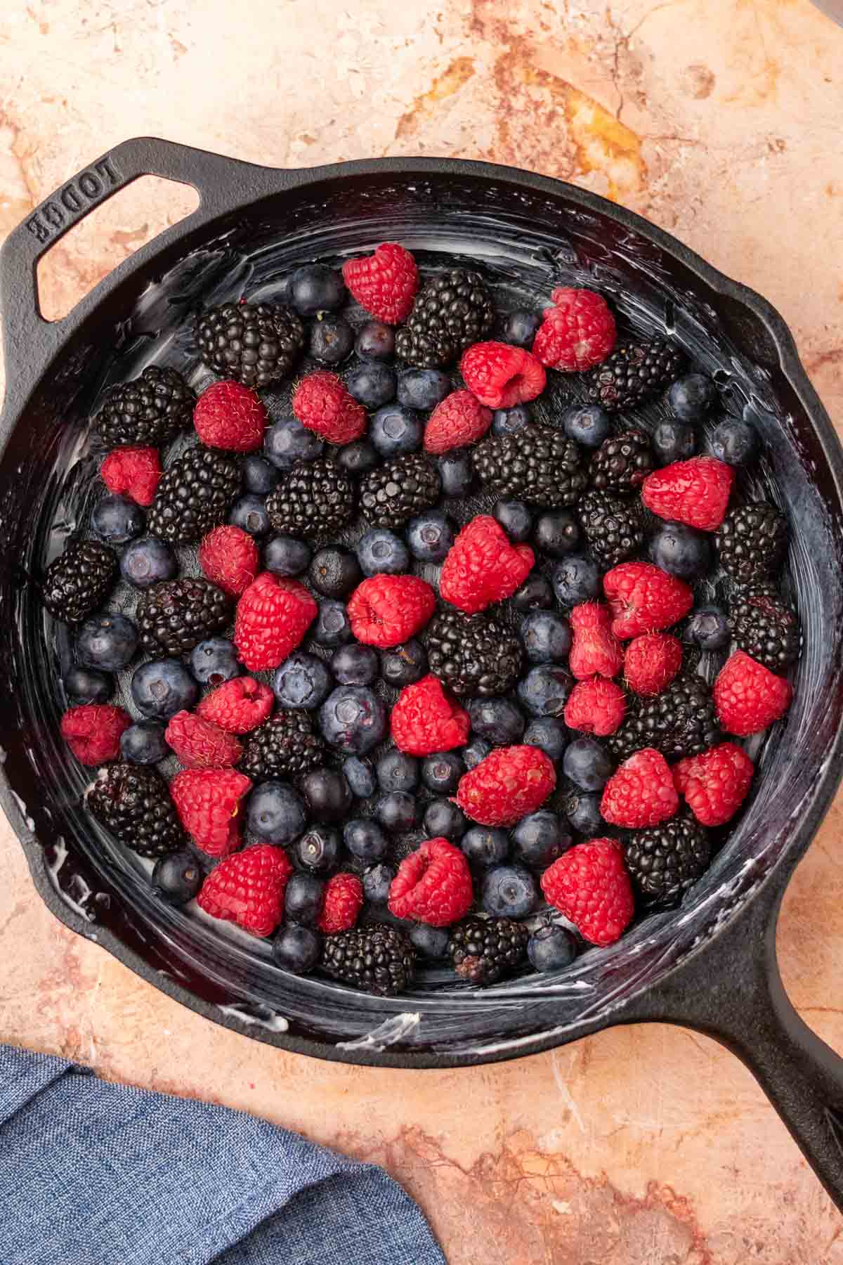 Mixed berries arranged in a single layer in a cast-iron skillet.