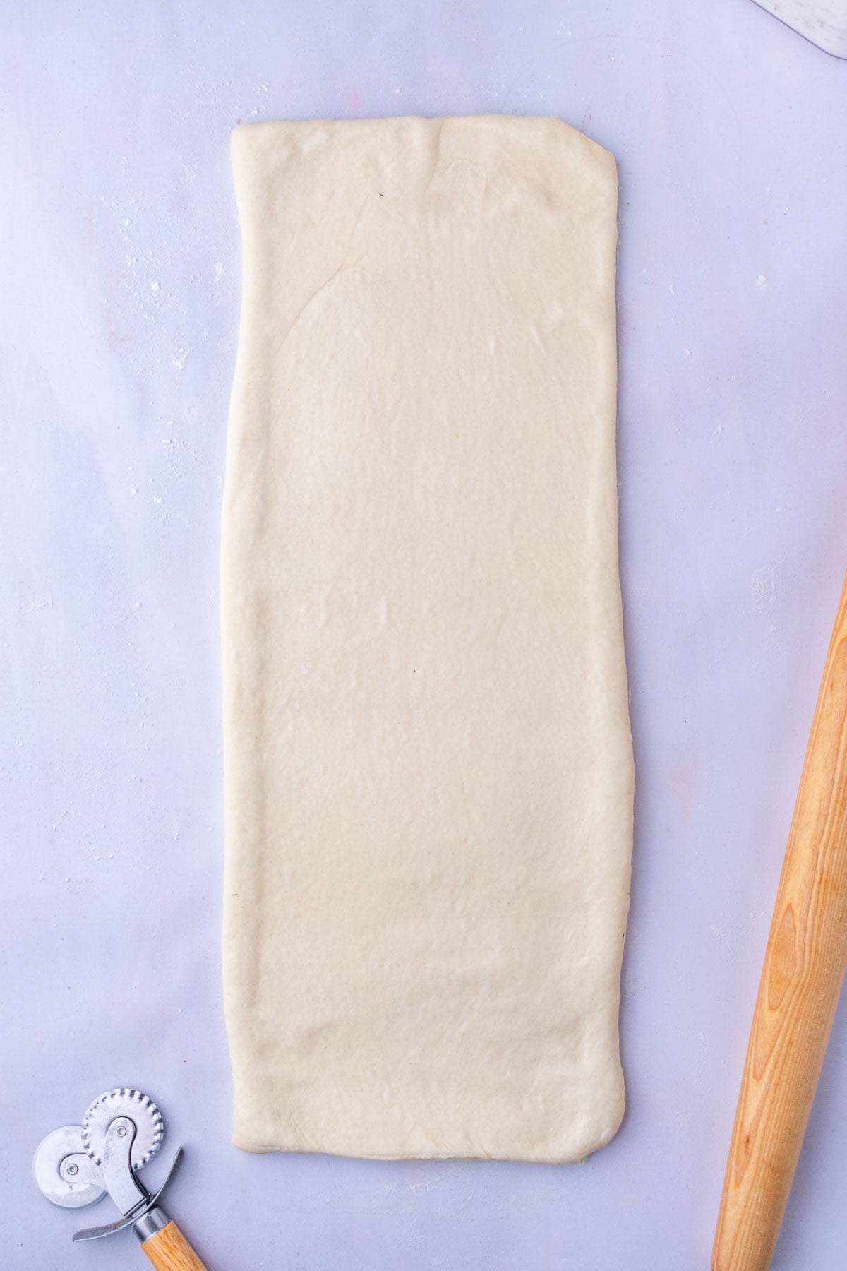 Sourdough croissant bread loaf dough rolled out into a long slab for folding.