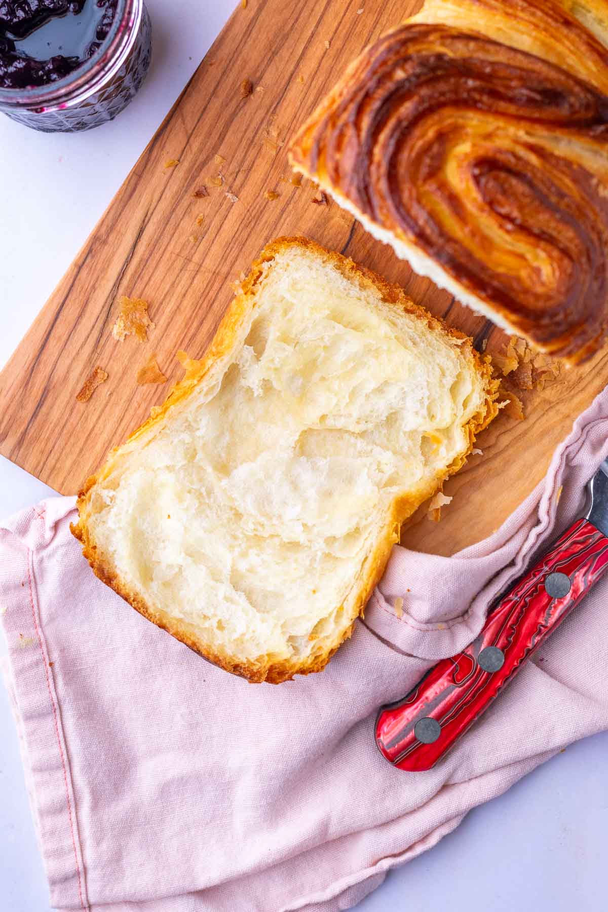 Sliced sourdough croissant bread loaf on a cutting board with a bread knife.