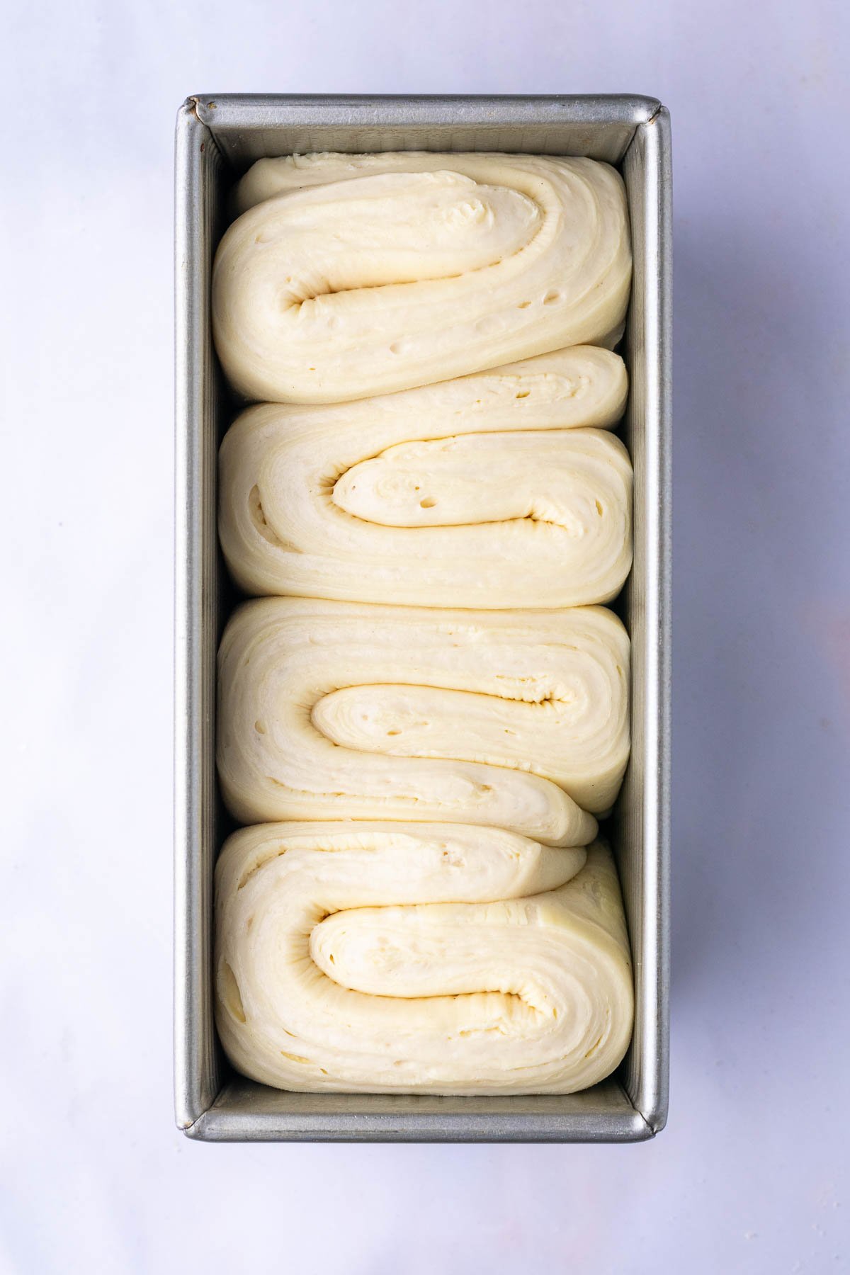 Sourdough croissant bread loaf in bread loaf pan doubled in size and puffy at the end of proofing.