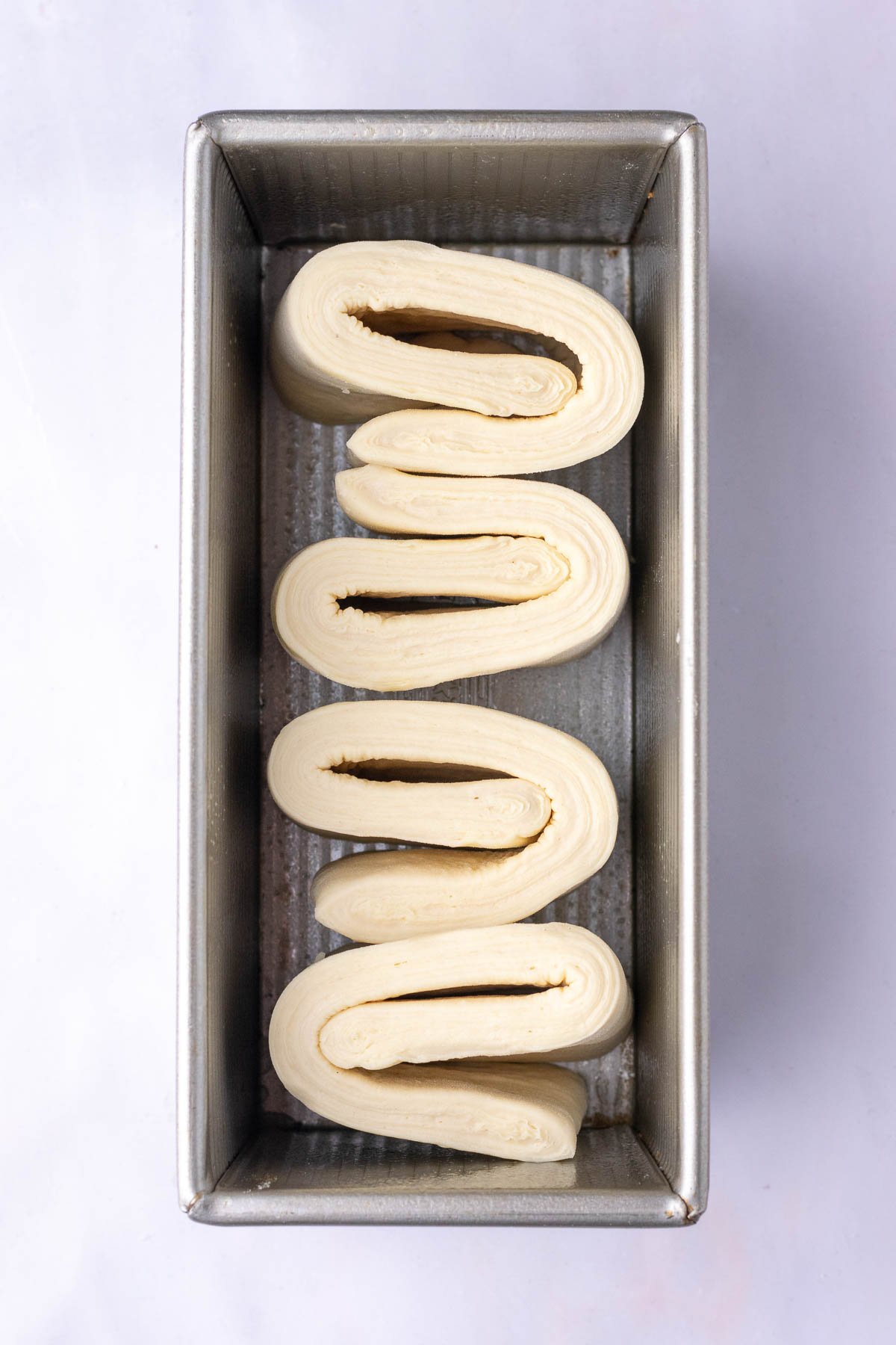 Sourdough croissant bread loaf dough in a bread loaf pan at the start of proofing.
