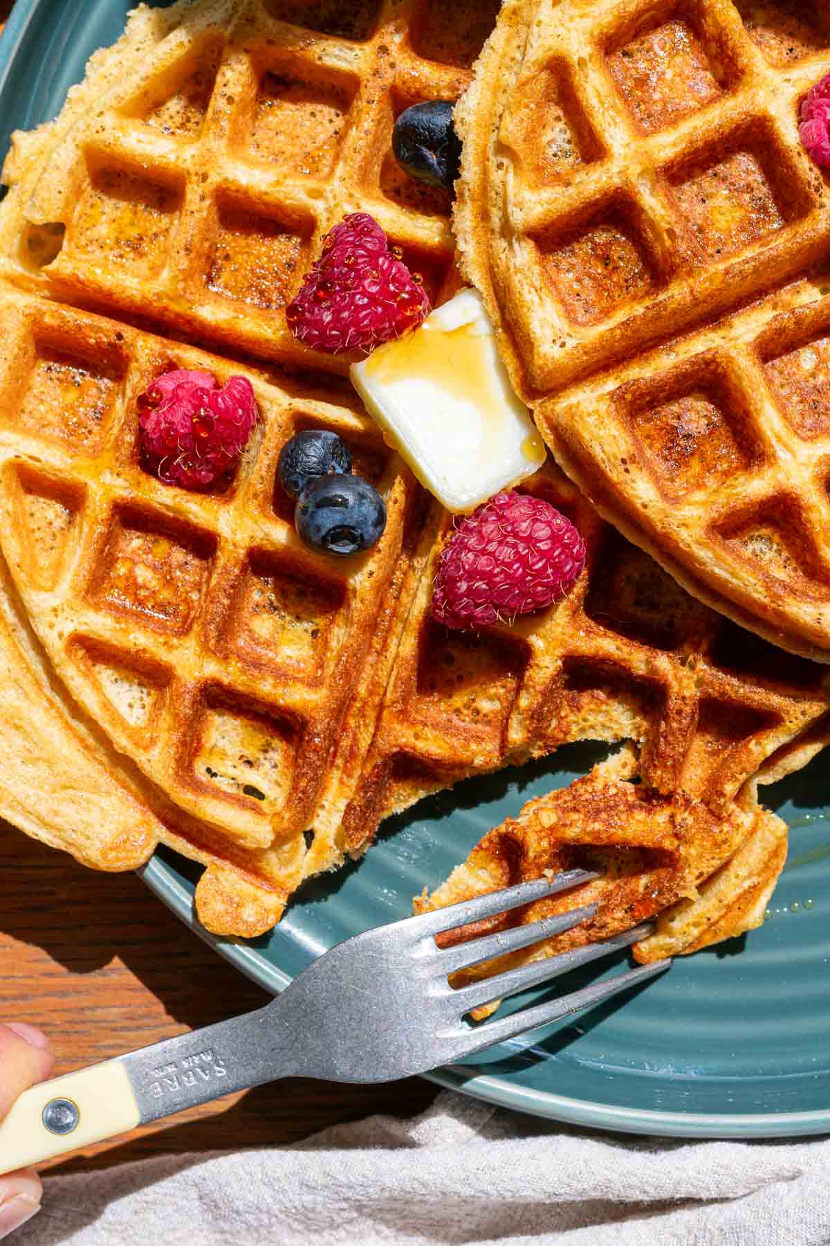 Taking bite out of sourdough einkorn waffles with a fork.
