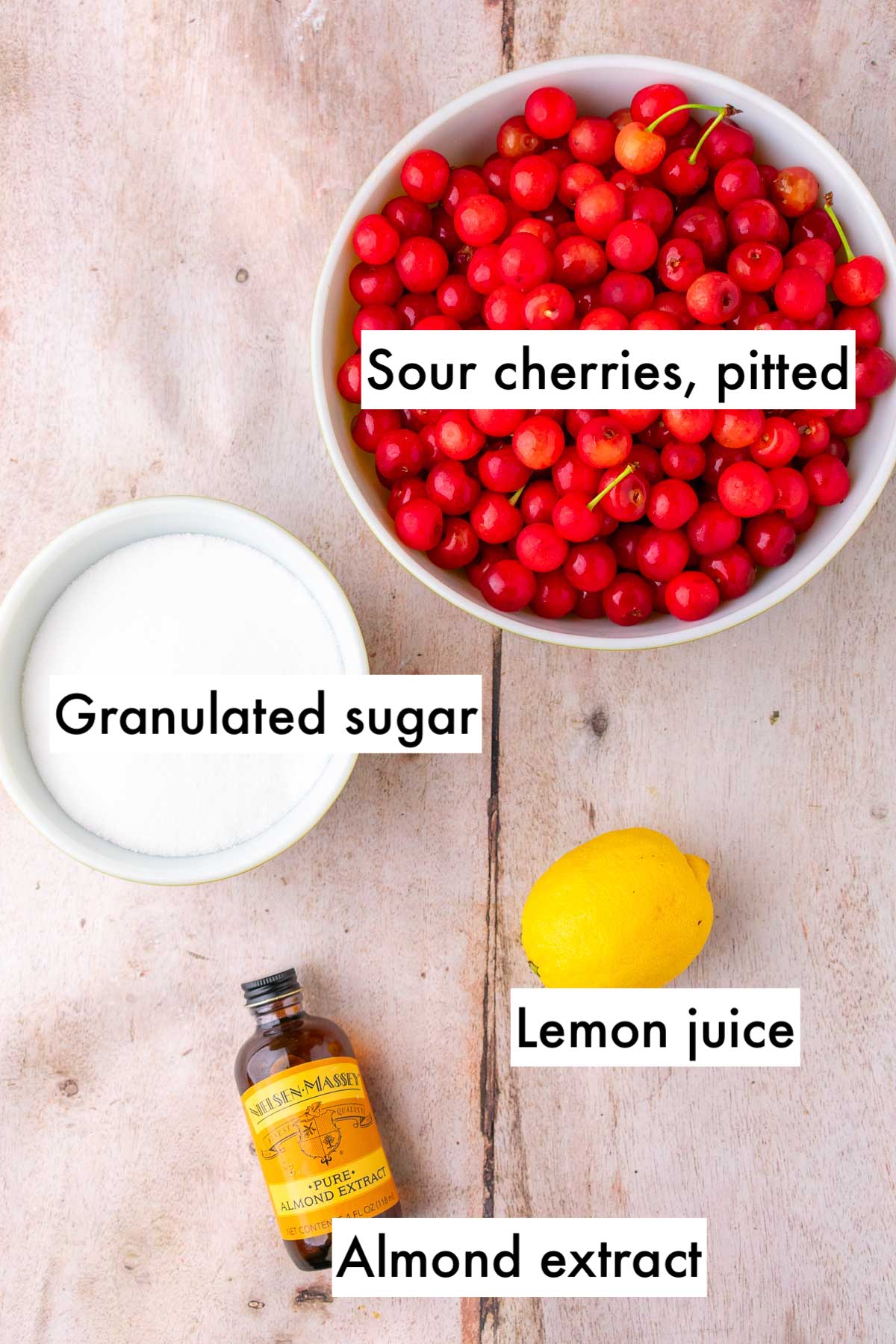Bowls of ingredients needed for sour cherry jam including pitted sour cherries, granulated sugar, lemon juice, and almond extract.