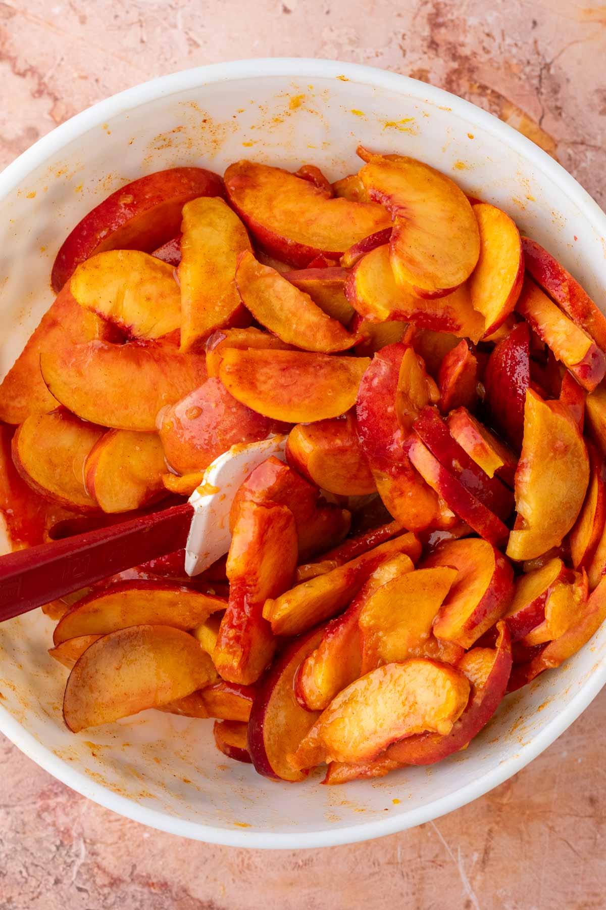 Sliced peaches for filling mixed in a bowl with a spatula.