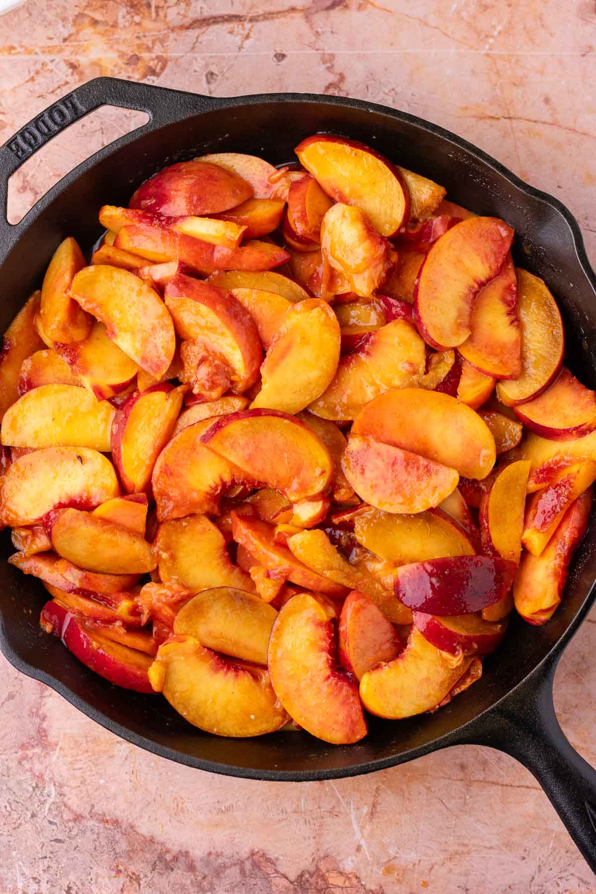Peach filling for cobbler in a cast-iron skillet.