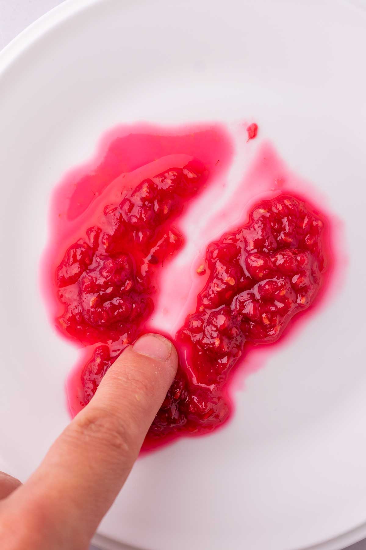 Finger dragging through runny Raspberry Rose Jam on a plate and doesn't pass the test.