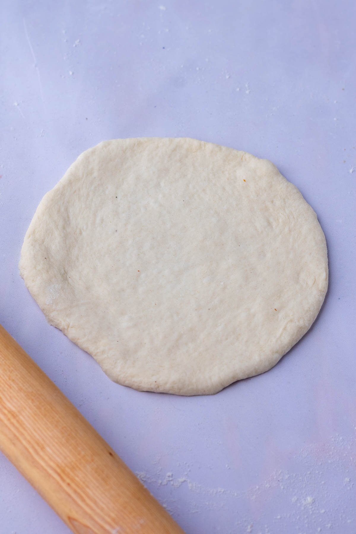 Rolled out sourdough pita bread into thin round with a rolling pin.