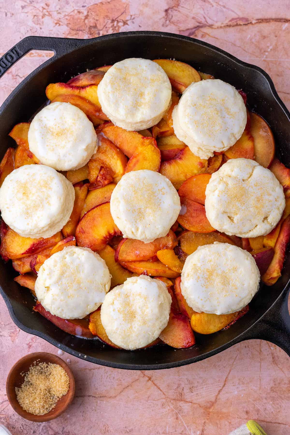 Sourdough peach cobbler with biscuits on top before baking.