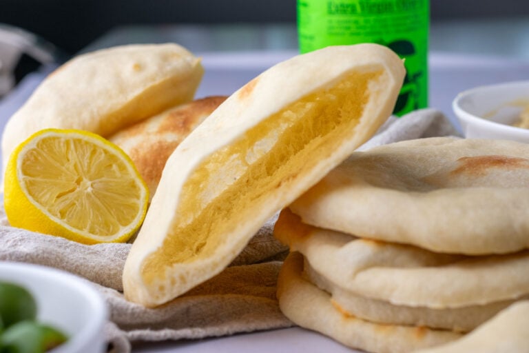 Fluffy stack of sourdough pita bread with pocket open on top one.