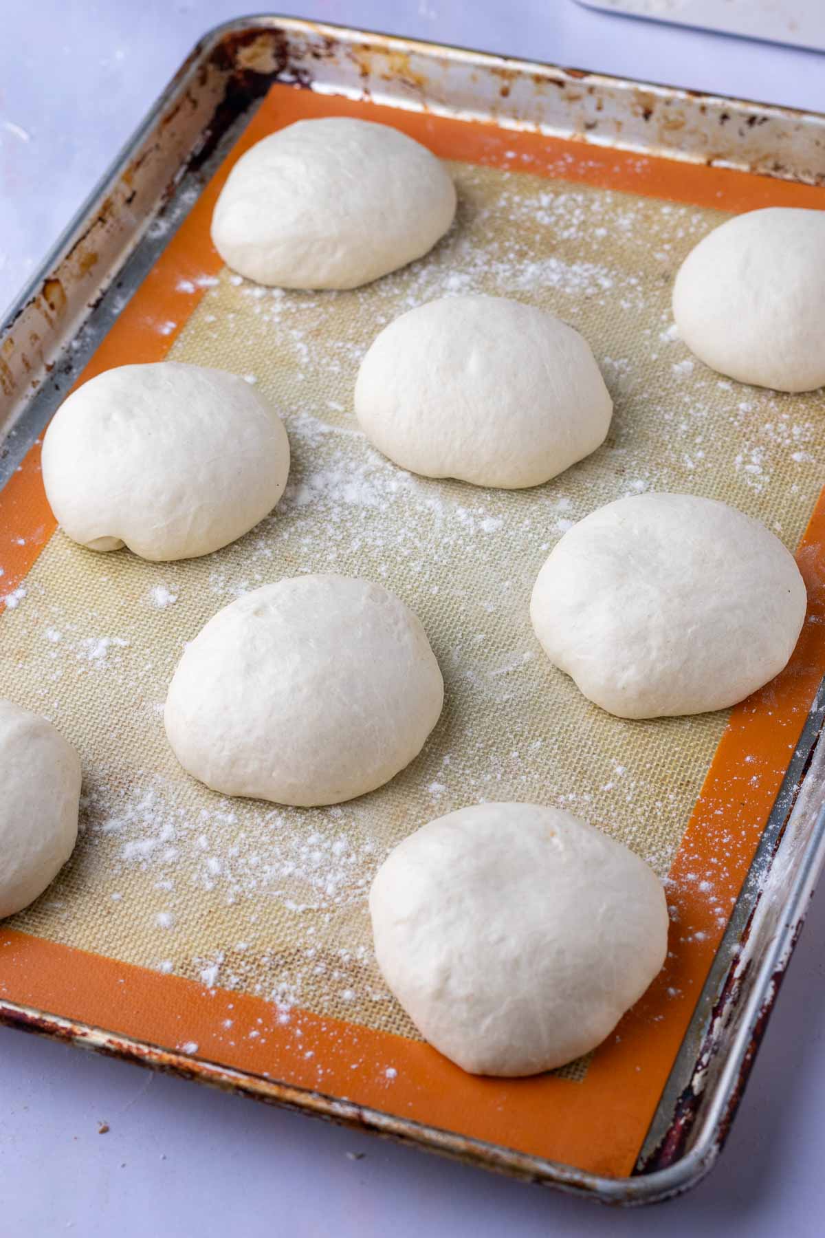 Proofed sourdough pita bread on a sheet pan doubled in size.