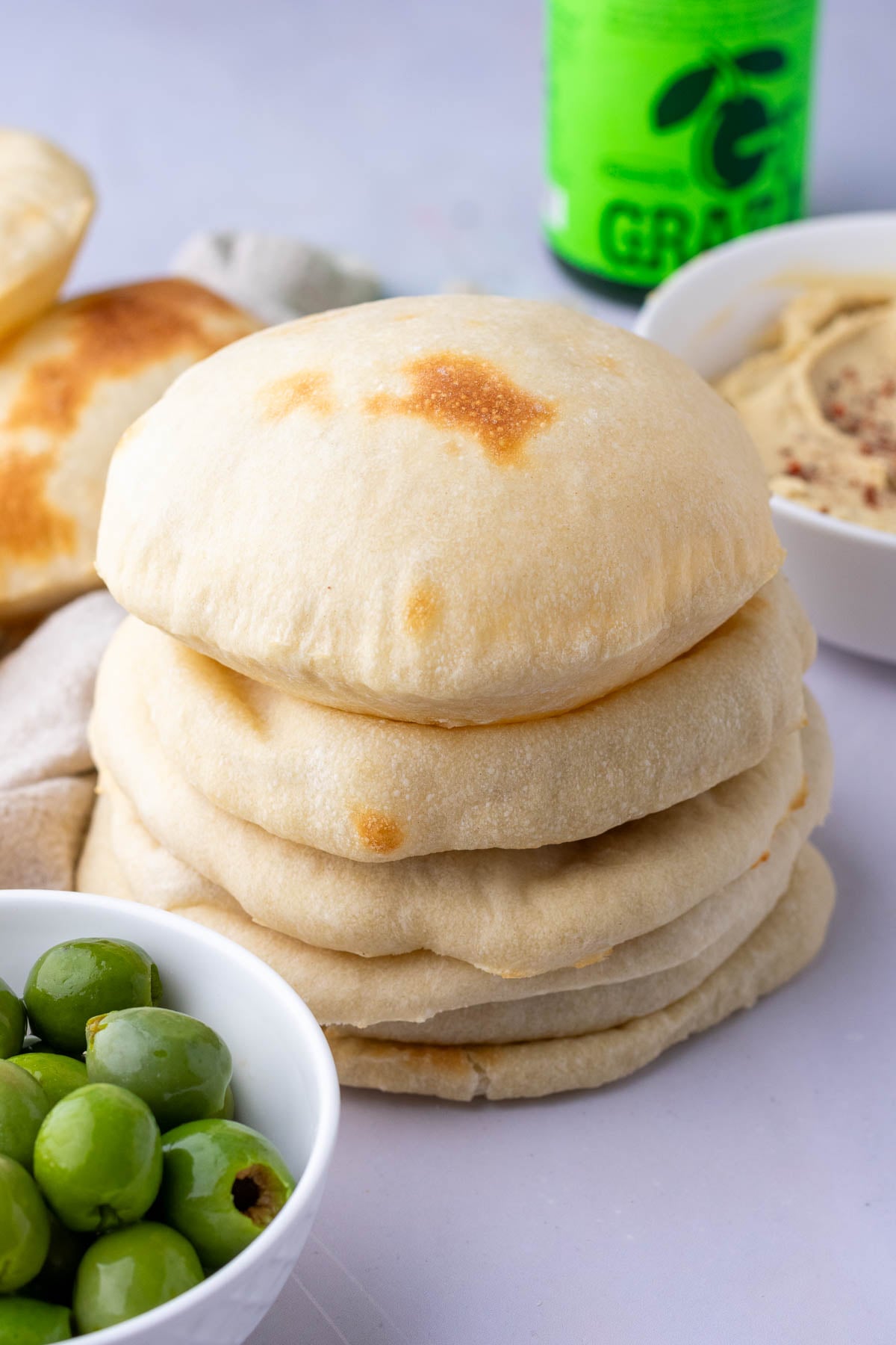 Stack of sourdough pita bread with olives and hummus.