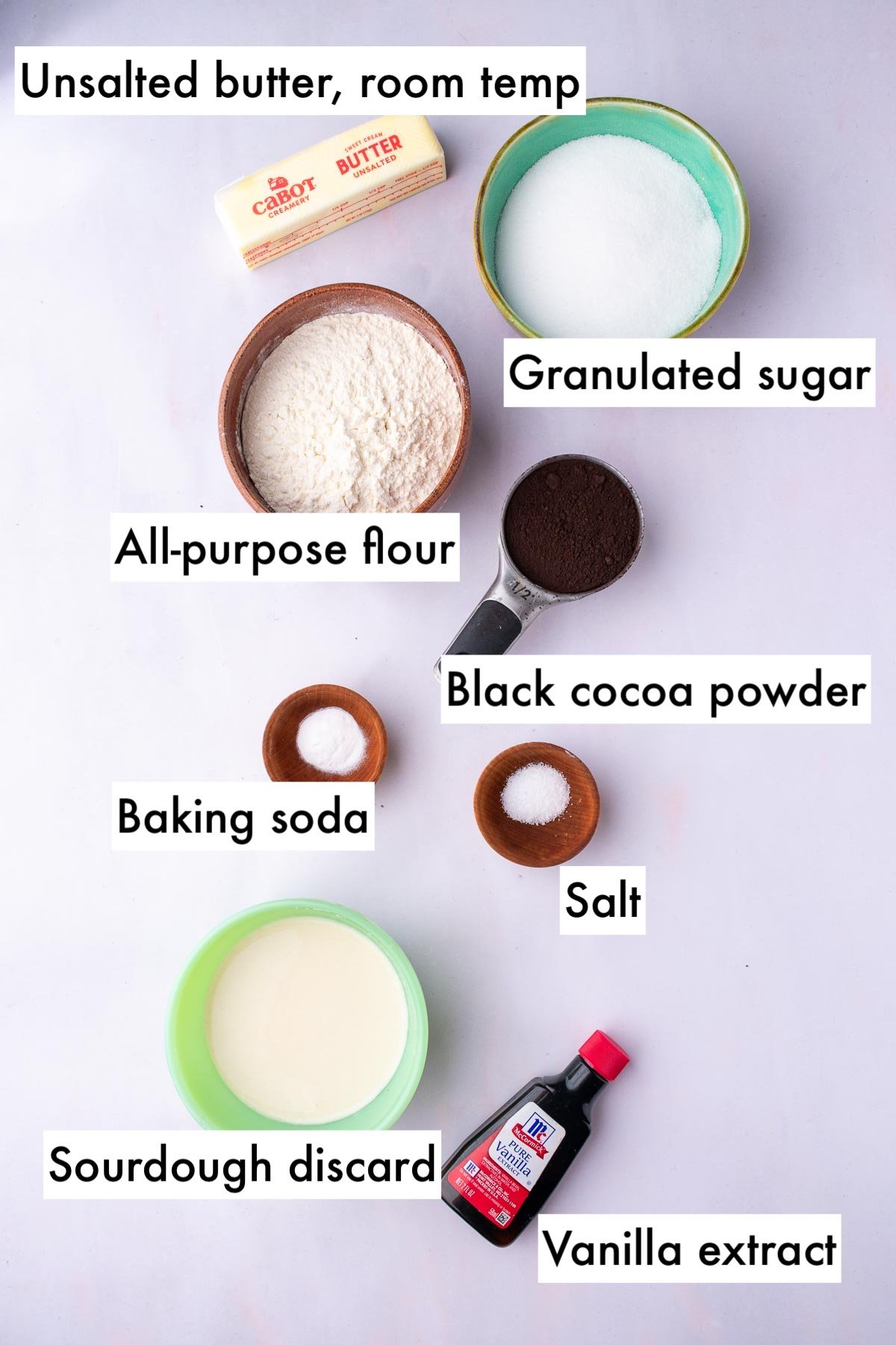 Labeled ingredients needed for sourdough oreos including unsalted butter, sugar, salt, baking soda, vanilla, sourdough discard, all-purpose flour, and black cocoa powder.