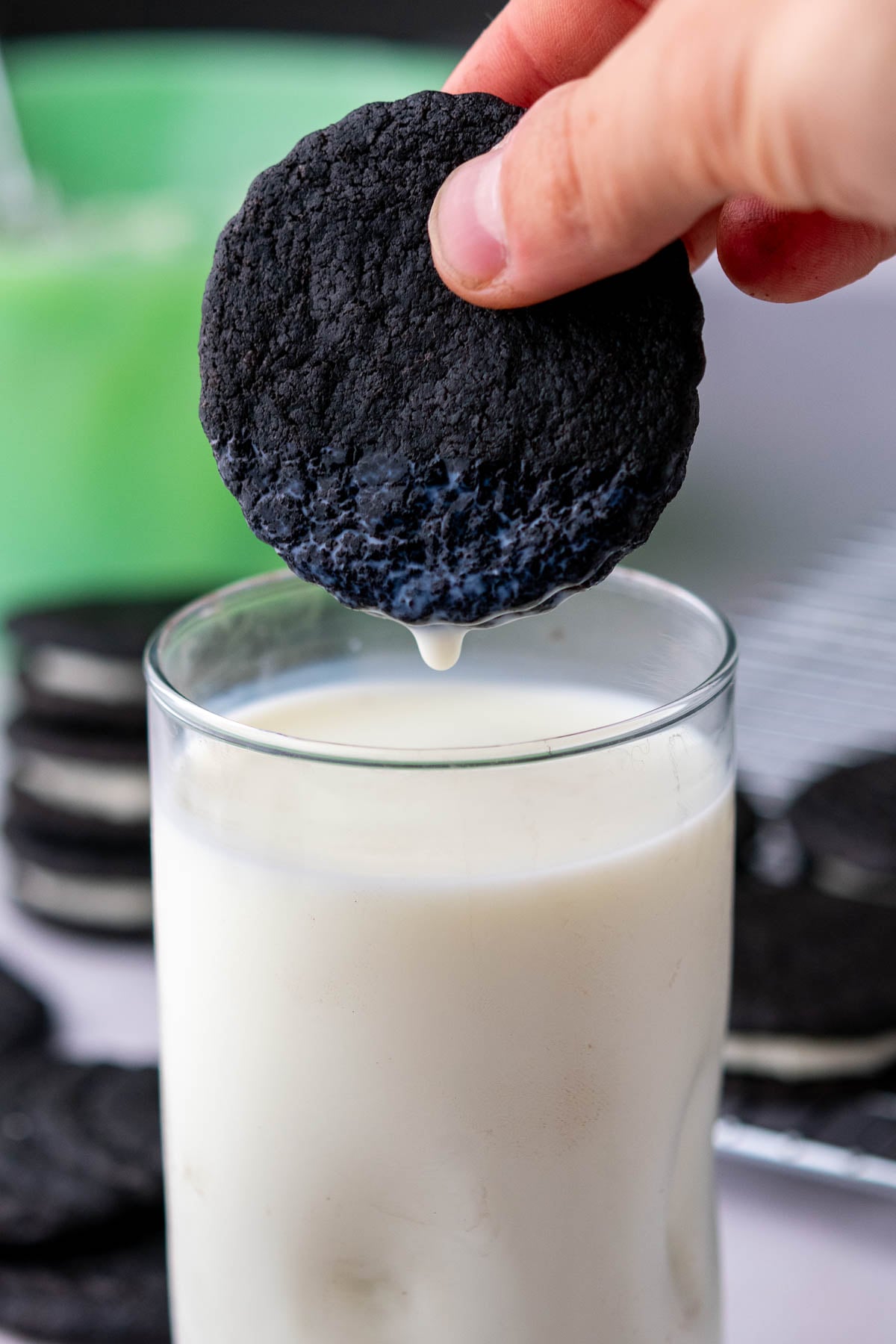 Hand dunking a sourdough oreo in a glass of milk.