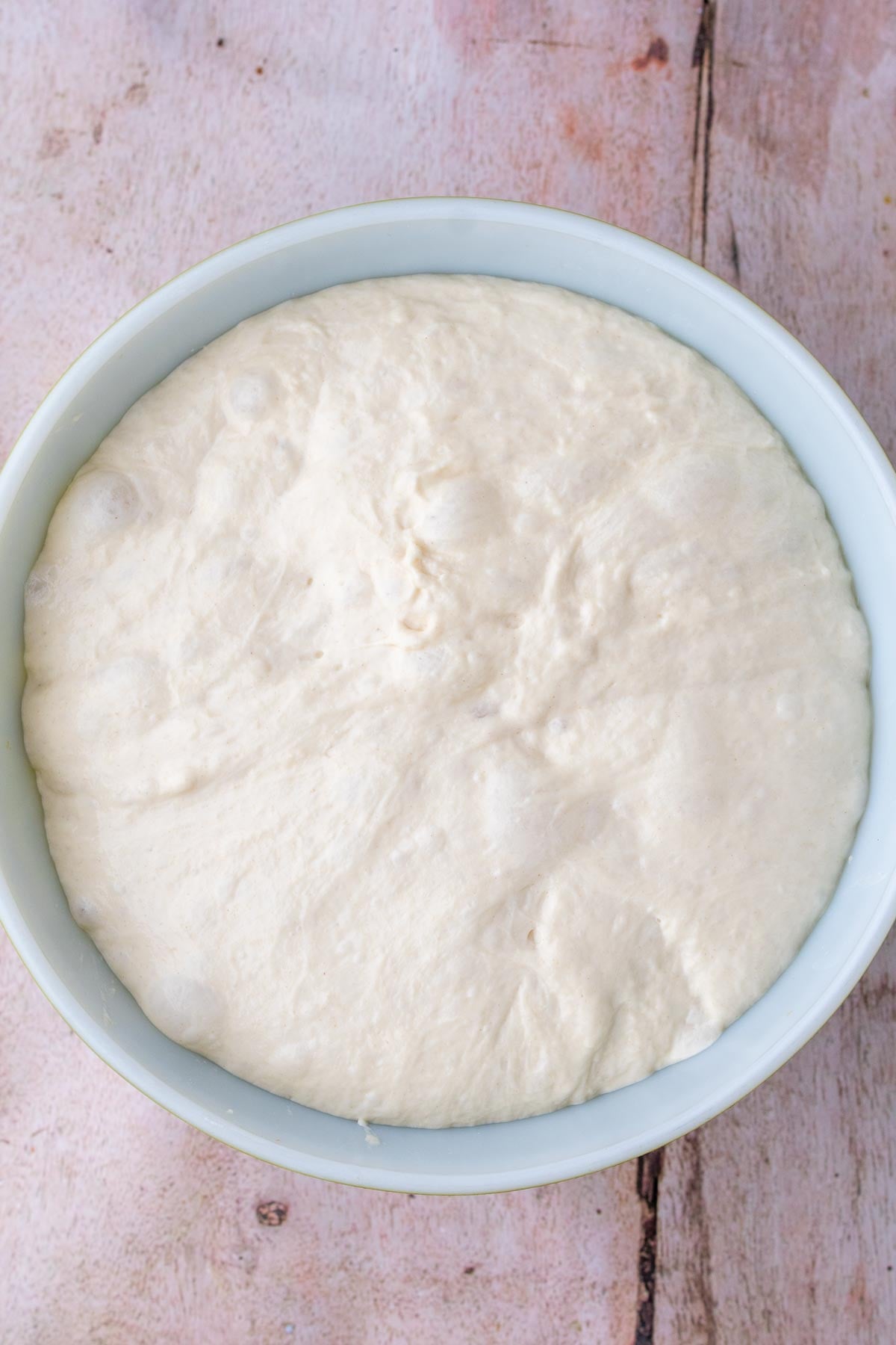 Sourdough pizza al taglio dough doubled in size and bubbly in bowl at the end of bulk fermentation.