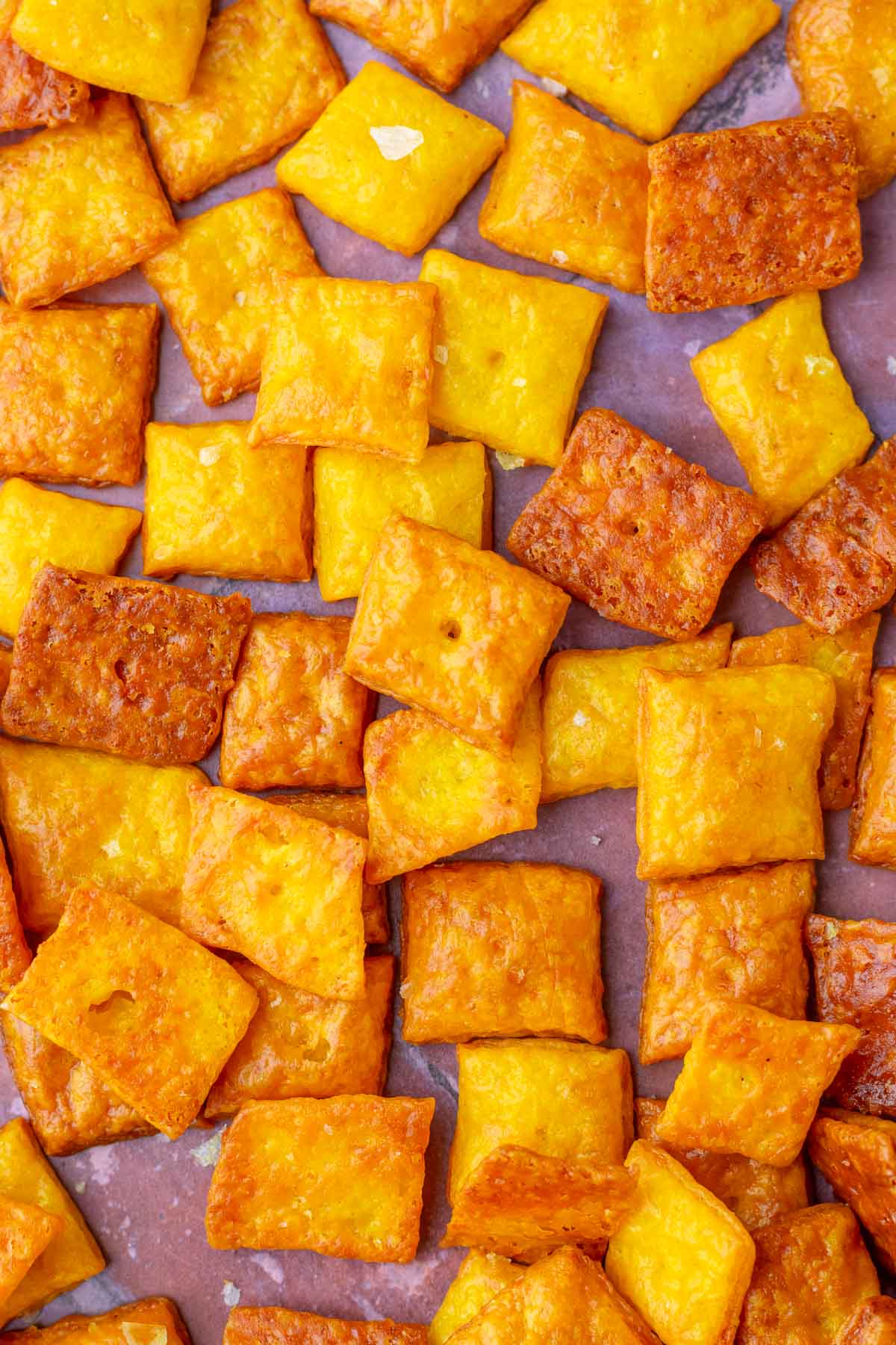 Many sourdough discard cheese crackers scattered on a surface.
