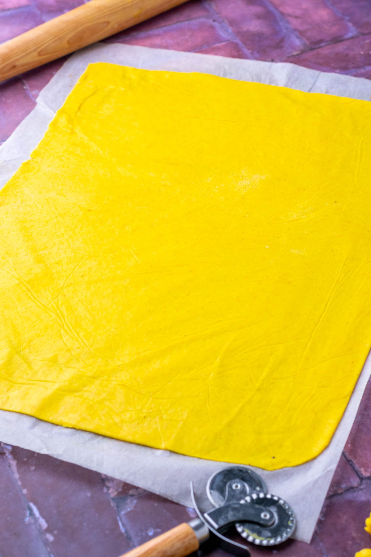 Thinly rolled out sourdough discard cheese cracker dough in a rectangle on parchment paper.