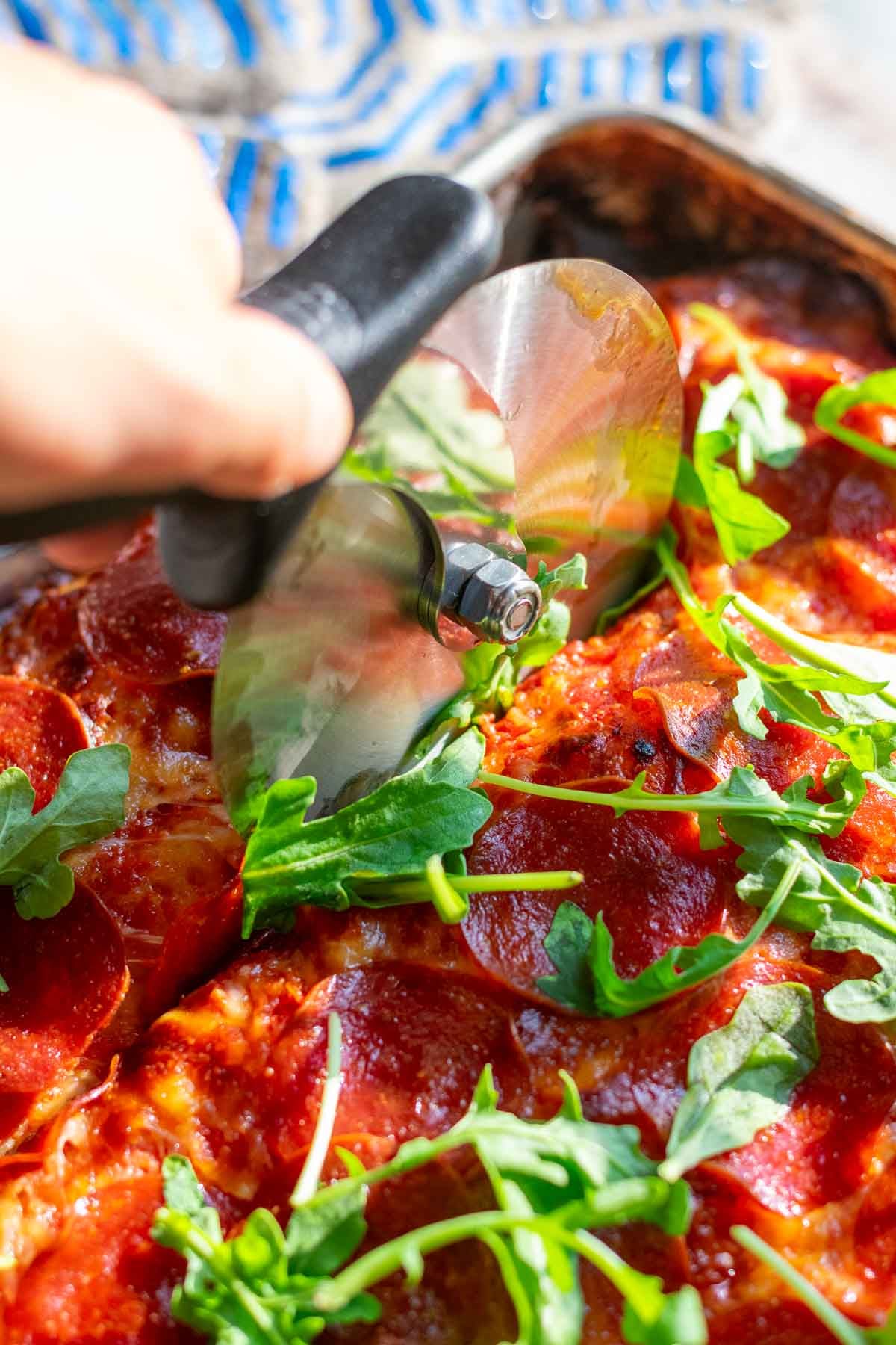 Slicing sourdough pizza al taglio with a pizza cutter.