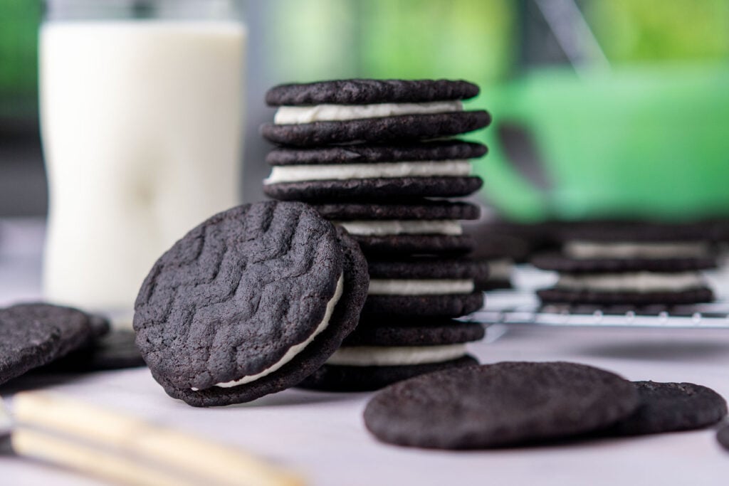 Stack of sourdough oreos with a glass of milk in the background.