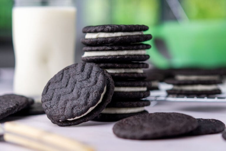Stack of sourdough oreos with a glass of milk in the background.