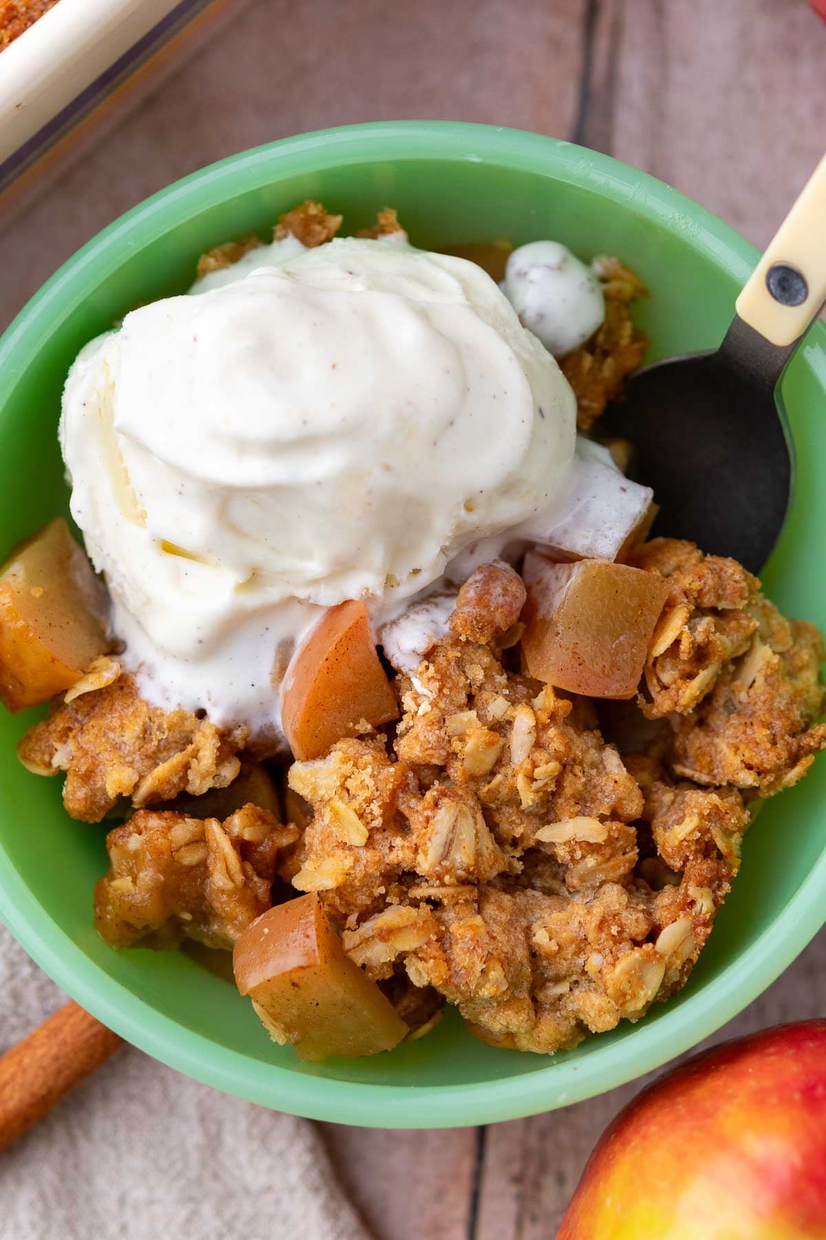 Bowl of sourdough apple crisp with a scoop of ice cream and a spoon.