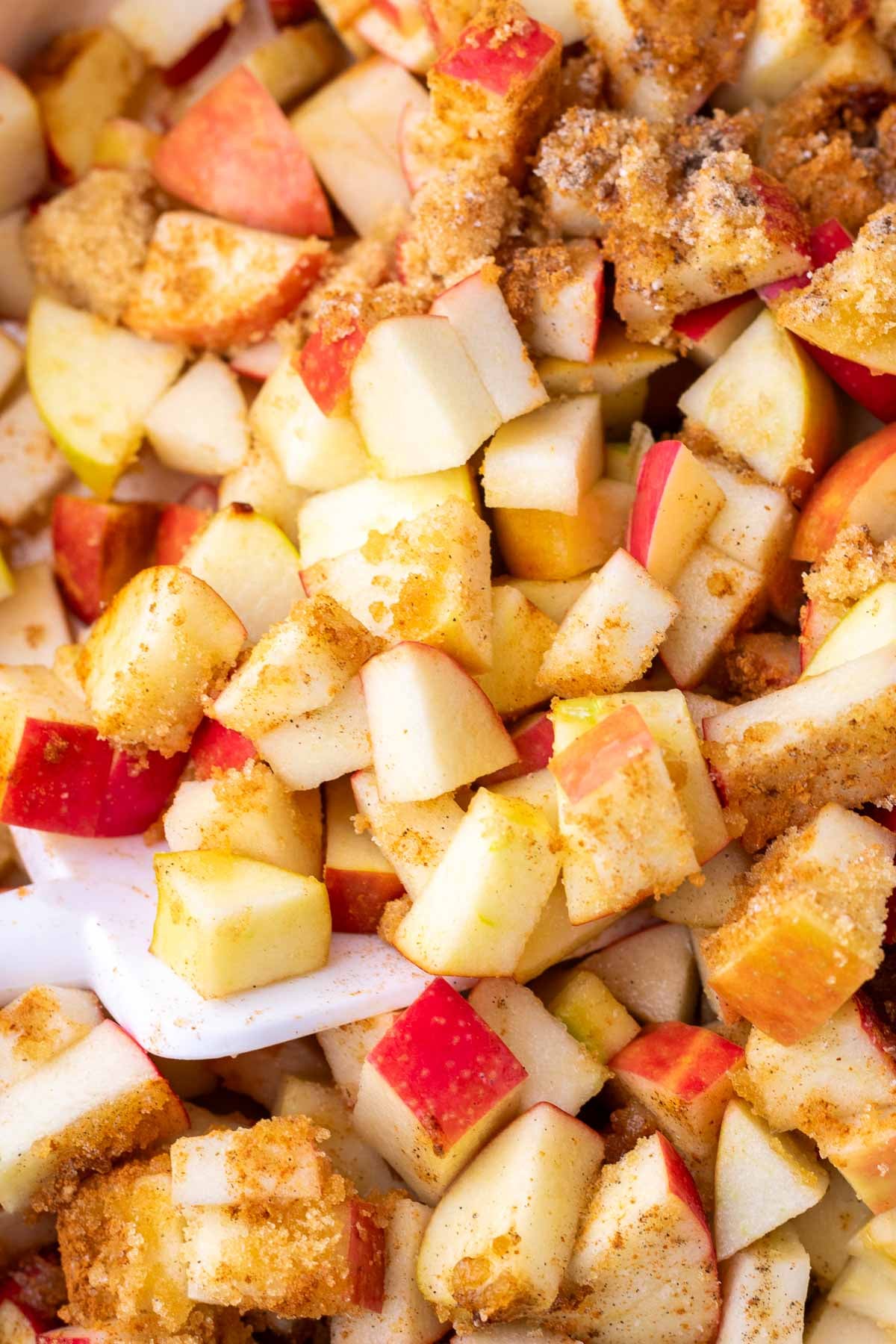 Mixing apple crisp filling with spices and sugar with a spatula.