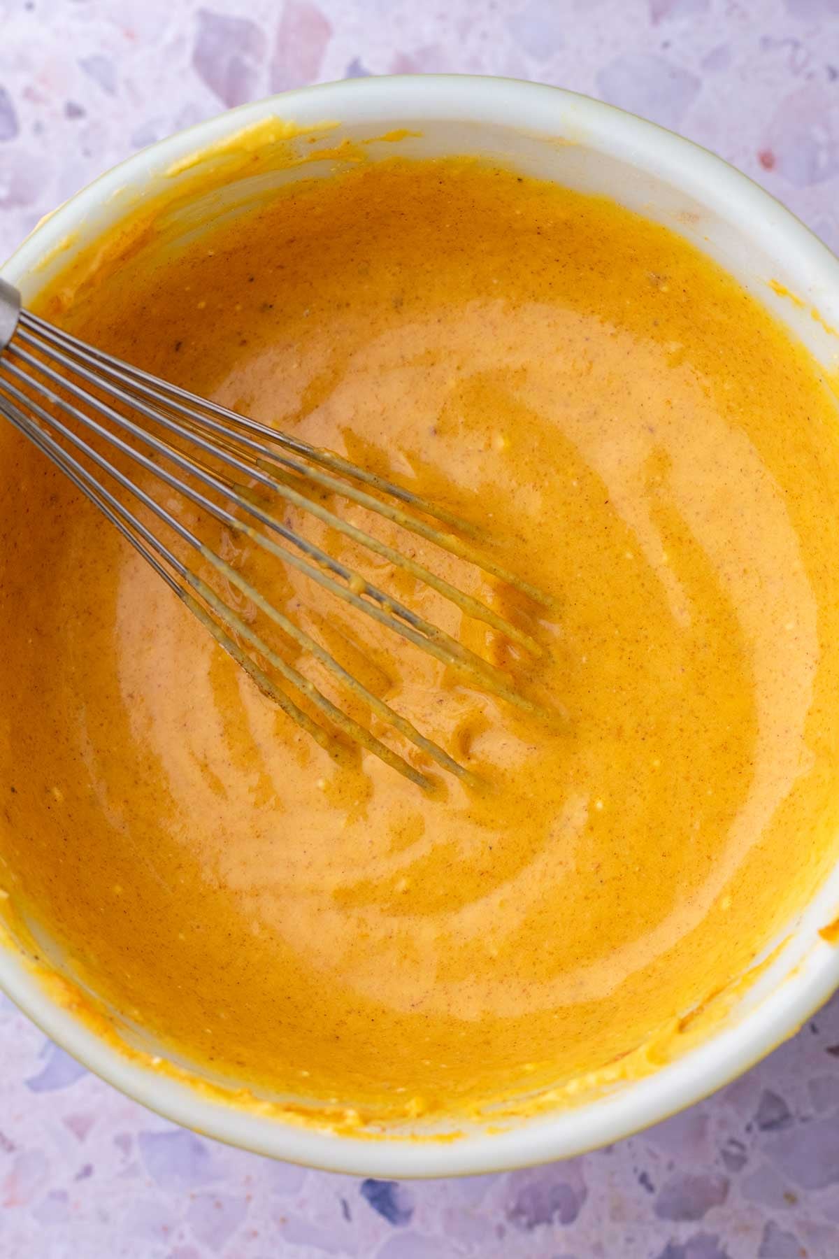 Mixing pumpkin cream cheese in a bowl with a whisk.