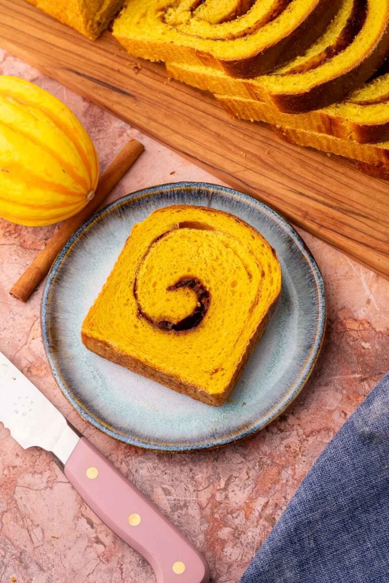 Slice of sourdough pumpkin cinnamon swirl bread on a plate with a bread knife.