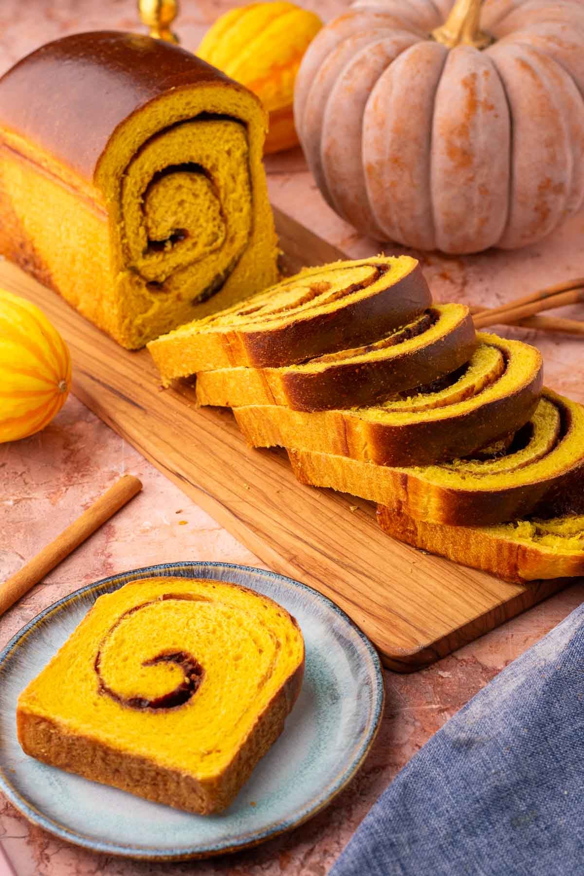 Slices of sourdough pumpkin cinnamon swirl bread with pumpkins in the background.