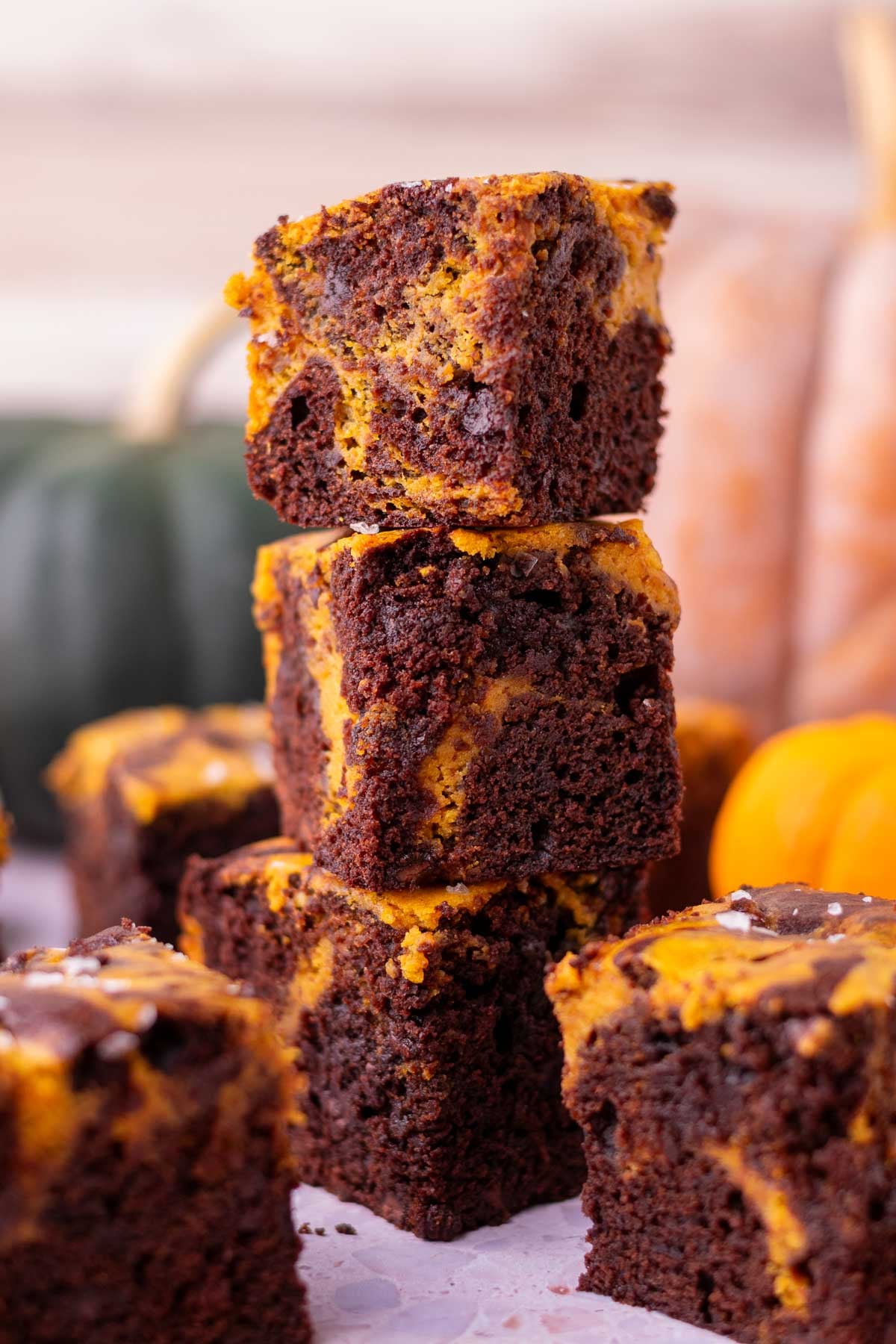 Stack of sourdough pumpkin brownies with pumpkin in the background.