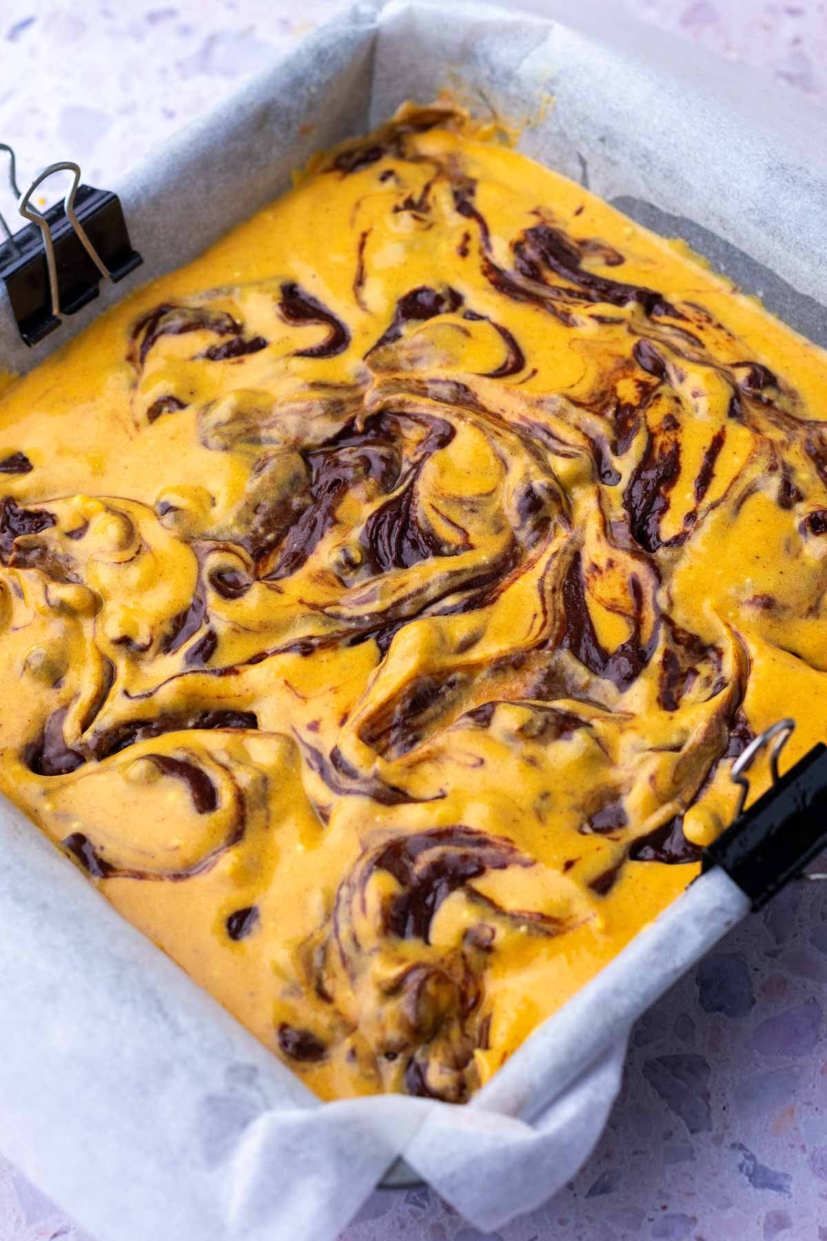 Swirled sourdough pumpkin brownies in a baking pan unbaked.