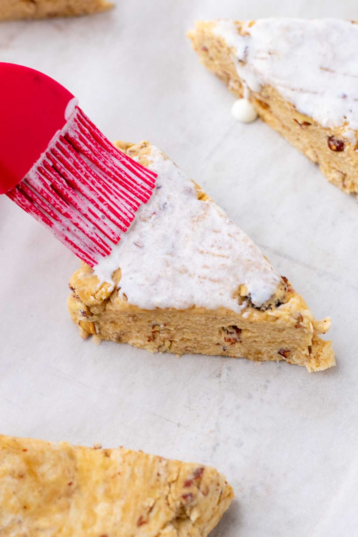 Brushing cream on a sourdough maple pecan scone before baking.