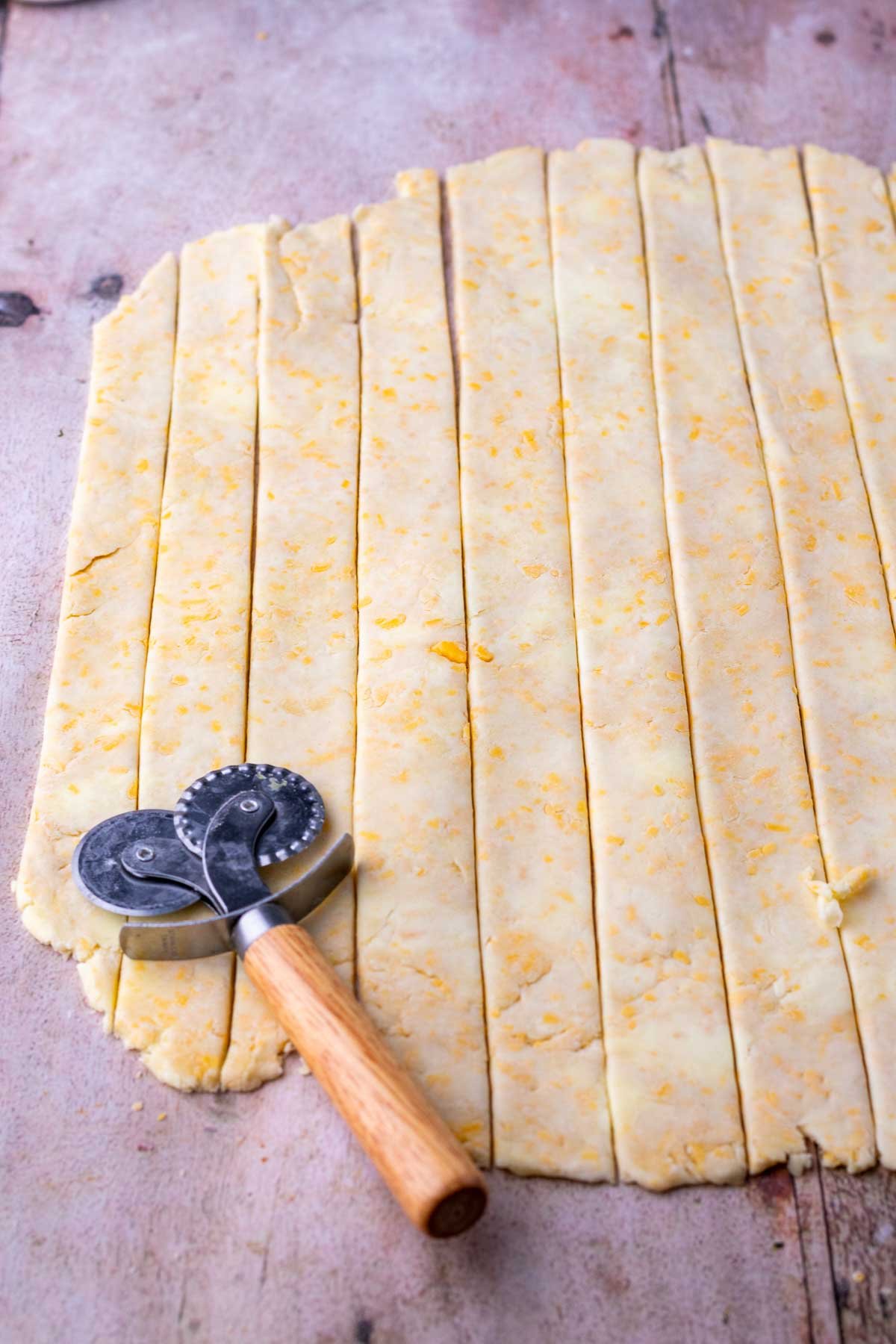 Slices of sourdough cheddar pie crust for lattice with a pastry wheel.