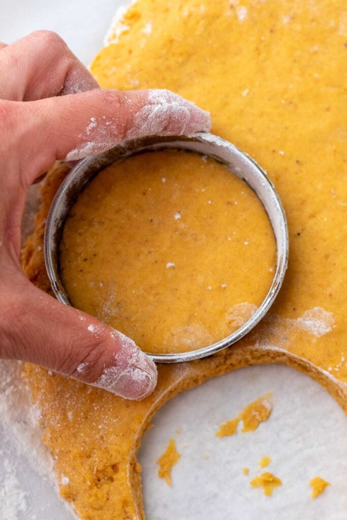 Cutting out sourdough pumpkin donuts with a cookie cutter.